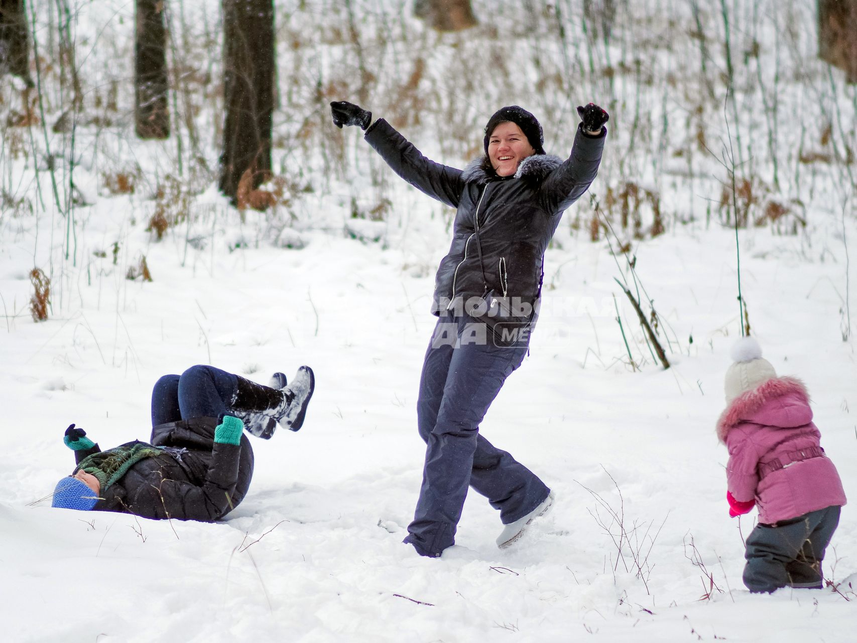 Женщина веселиться с двумя детьми в зимнем лесу.