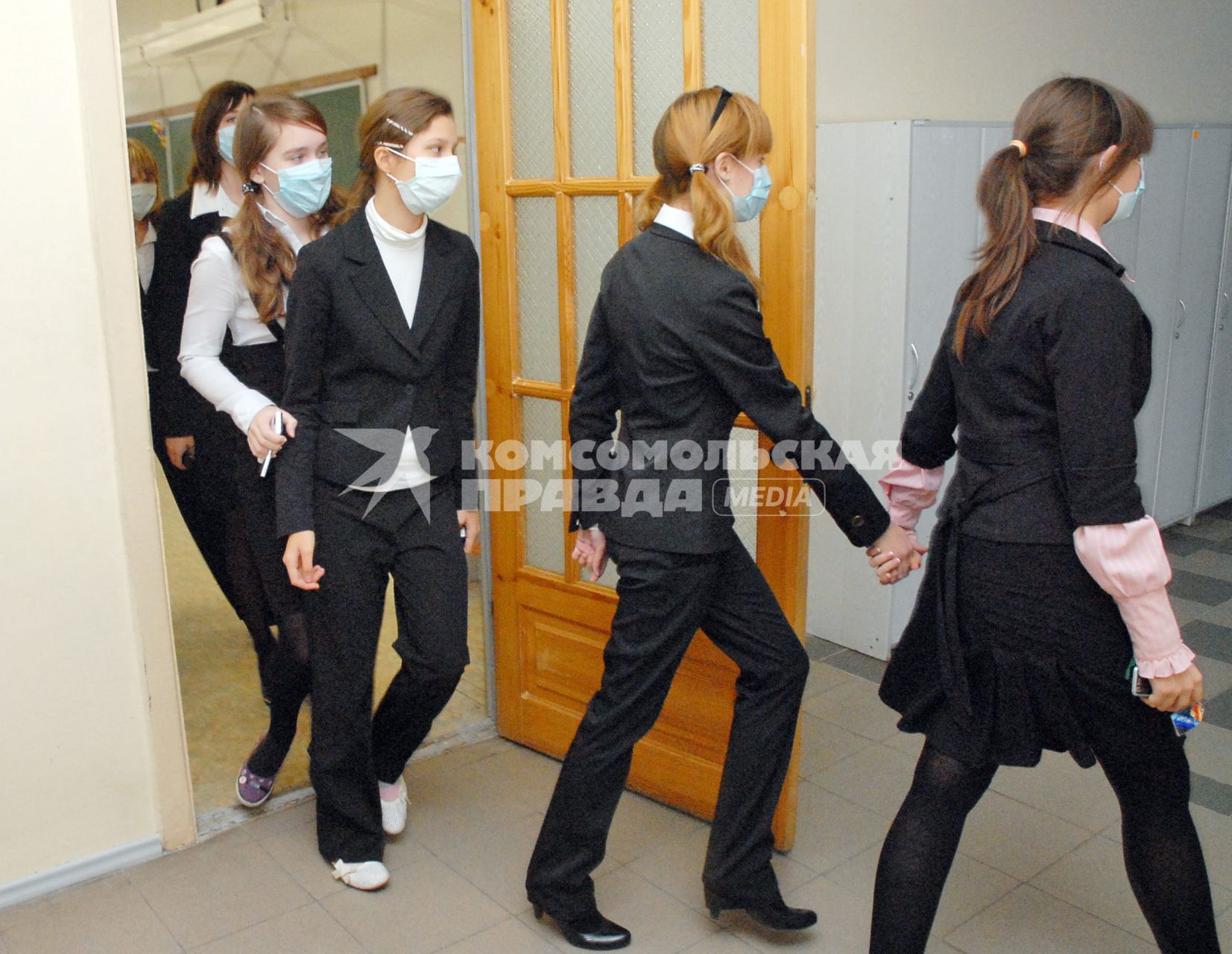 Школьники в медицинских повязках выходят из класса в коридор на перемену.