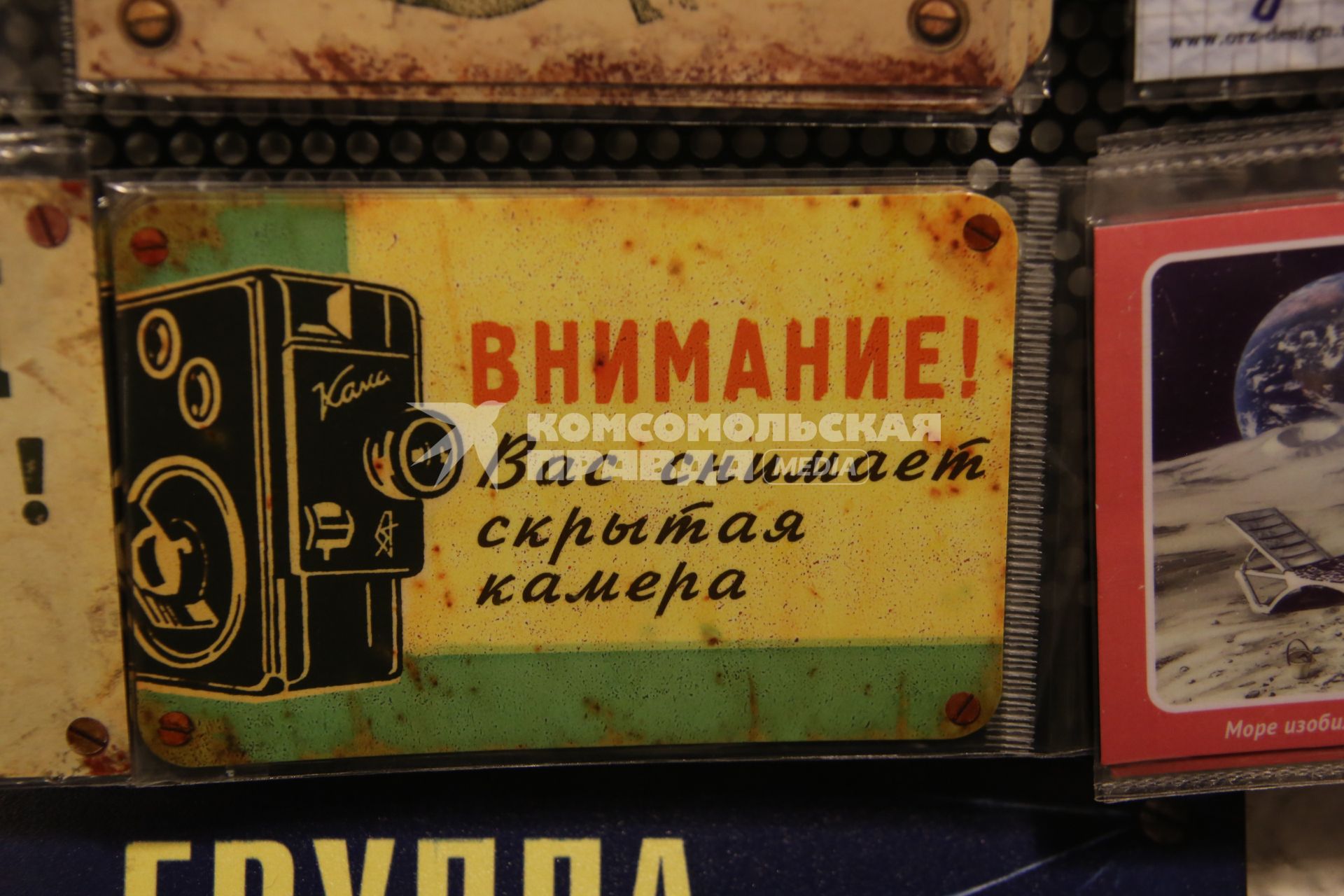 Магазин оригинальных подарков. На снимке: заламинированная табличка `Внимание! Вас снимает скрытая камера`.