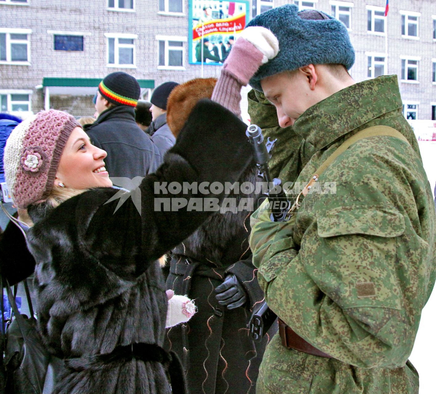 Девушка поправляет головной убор на солдате.