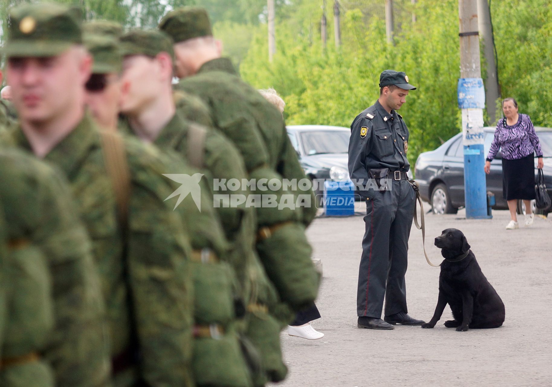 Полицейский кинолог с собакой у колонны призывников.
