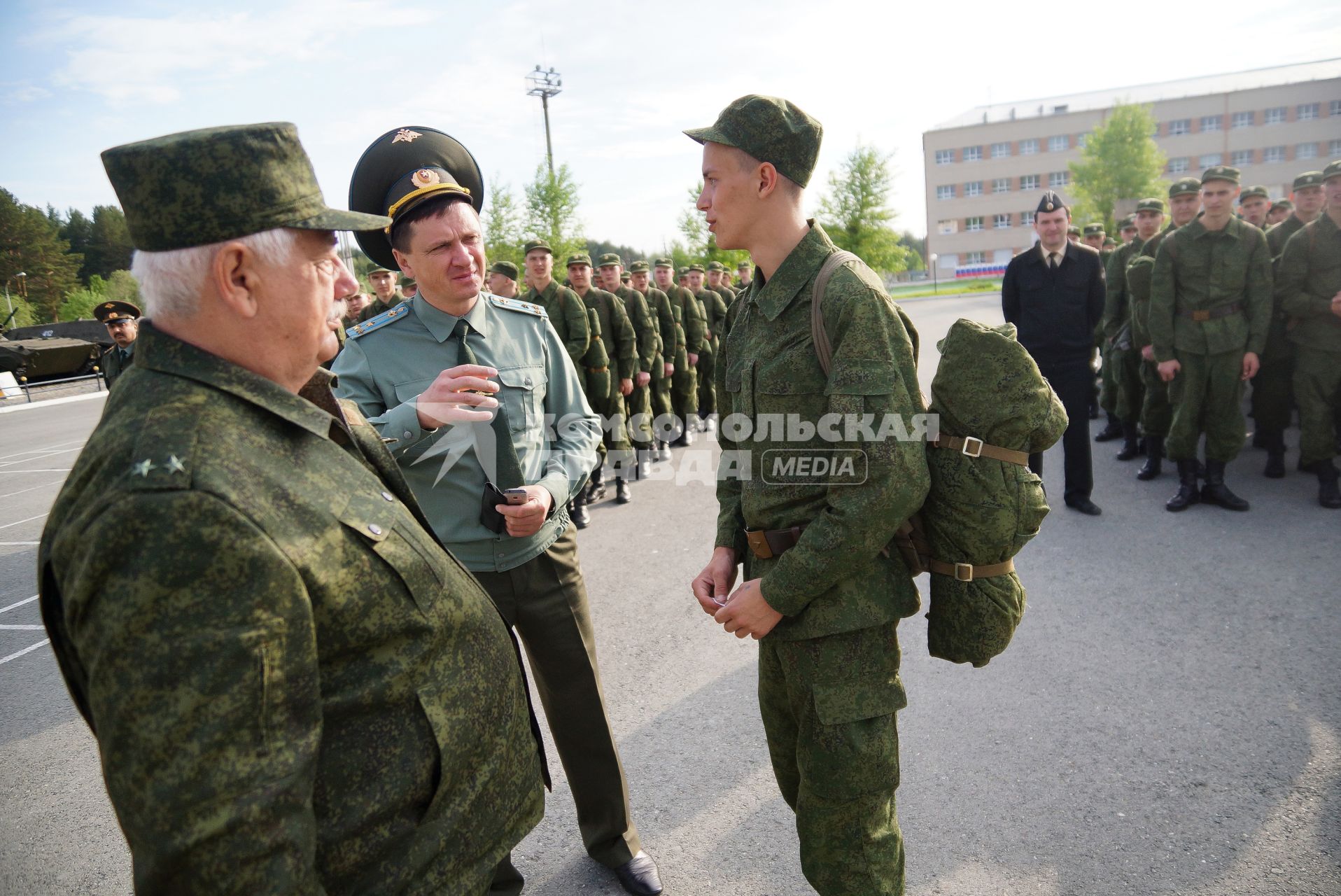 Офицеры разговаривают с новобранцем на плацу.