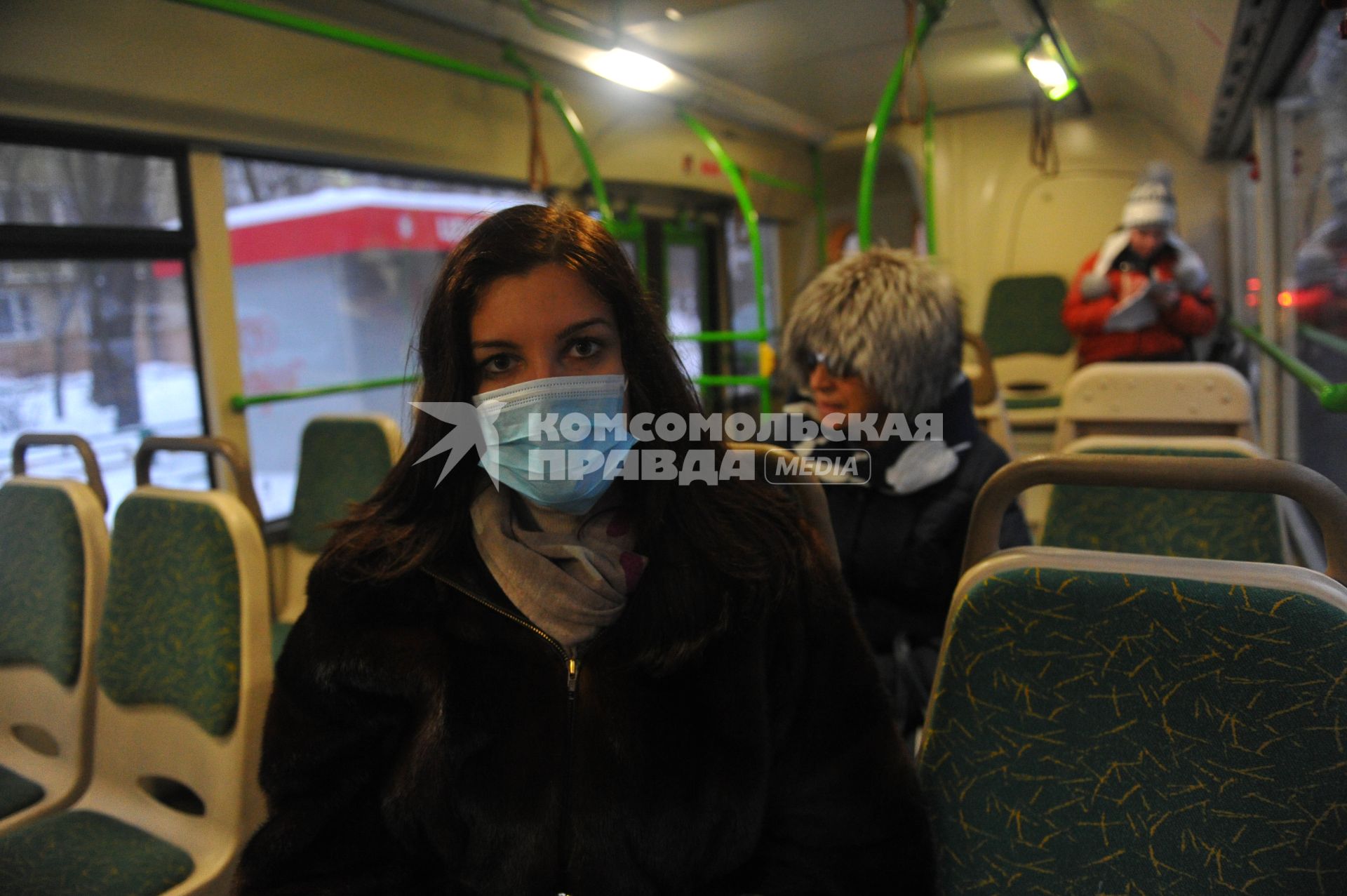 Девушка в медицинской маске в общественном транспорте.