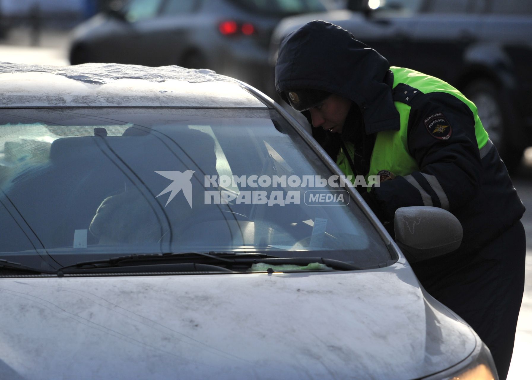 Сотрудник ДПС проверяет документы у водителя автомобиля.