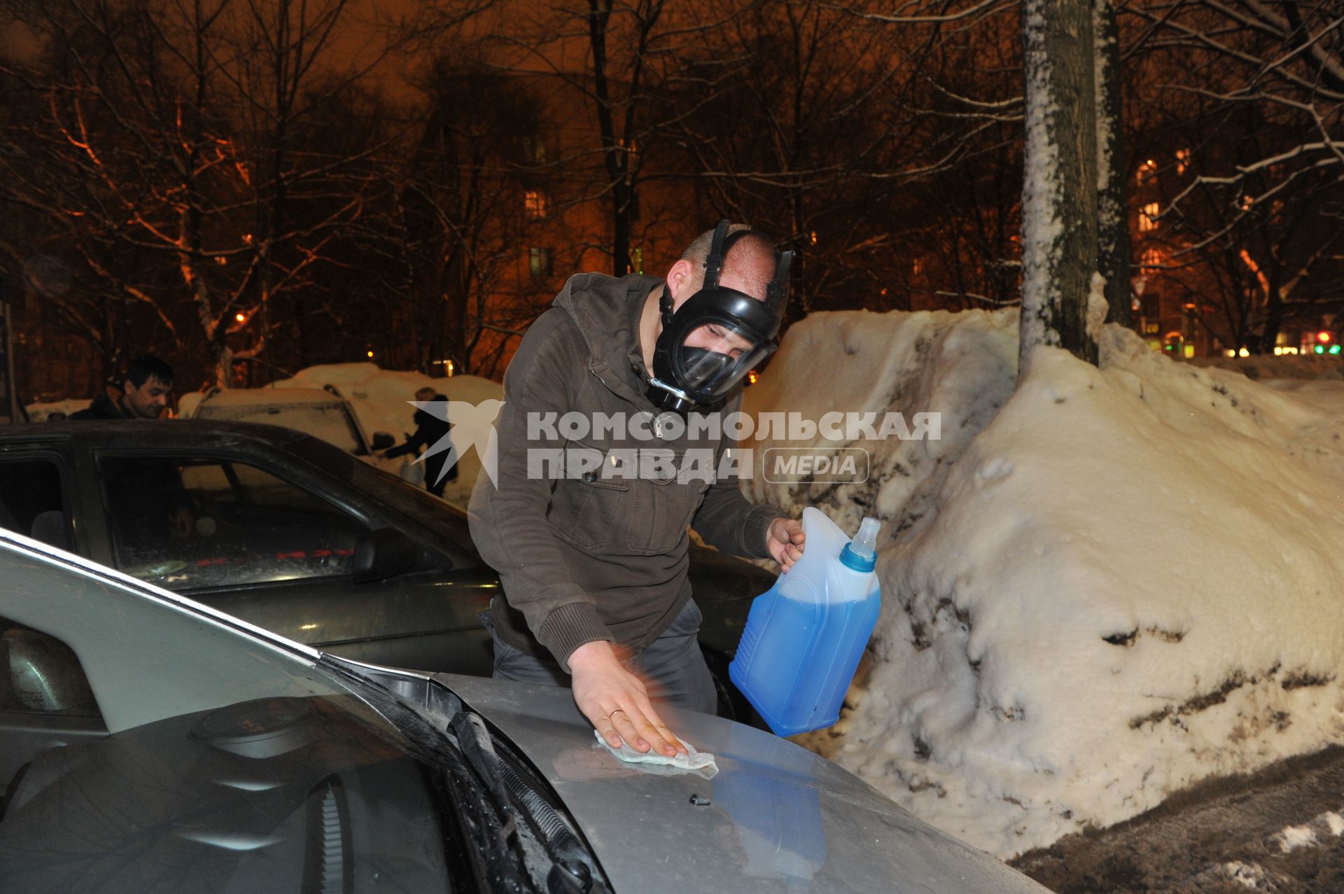 Молодой человек протирает автомобиль незамерзающей жидкостью.