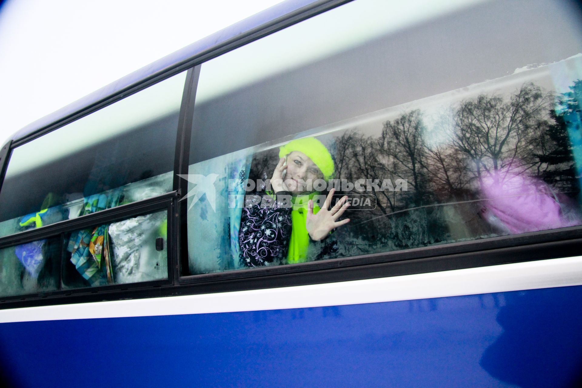 Старт патриотическая акции `Снежный десант`. На снимке: девушка в яркой зимней одежде сидит в автобусе, разговаривает по мобильному телефону и машет рукой.