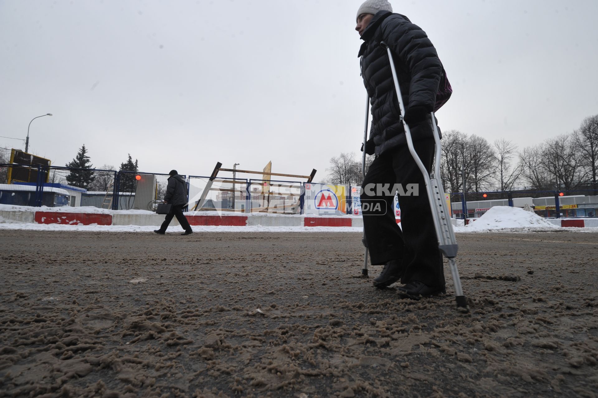 Изменения транспортного движения в районе метро `Динамо` в связи со строительством станции метрополитена `Петровский парк`. На снимке: пешеход с костылями у временного ограждения у метро `Динамо`.