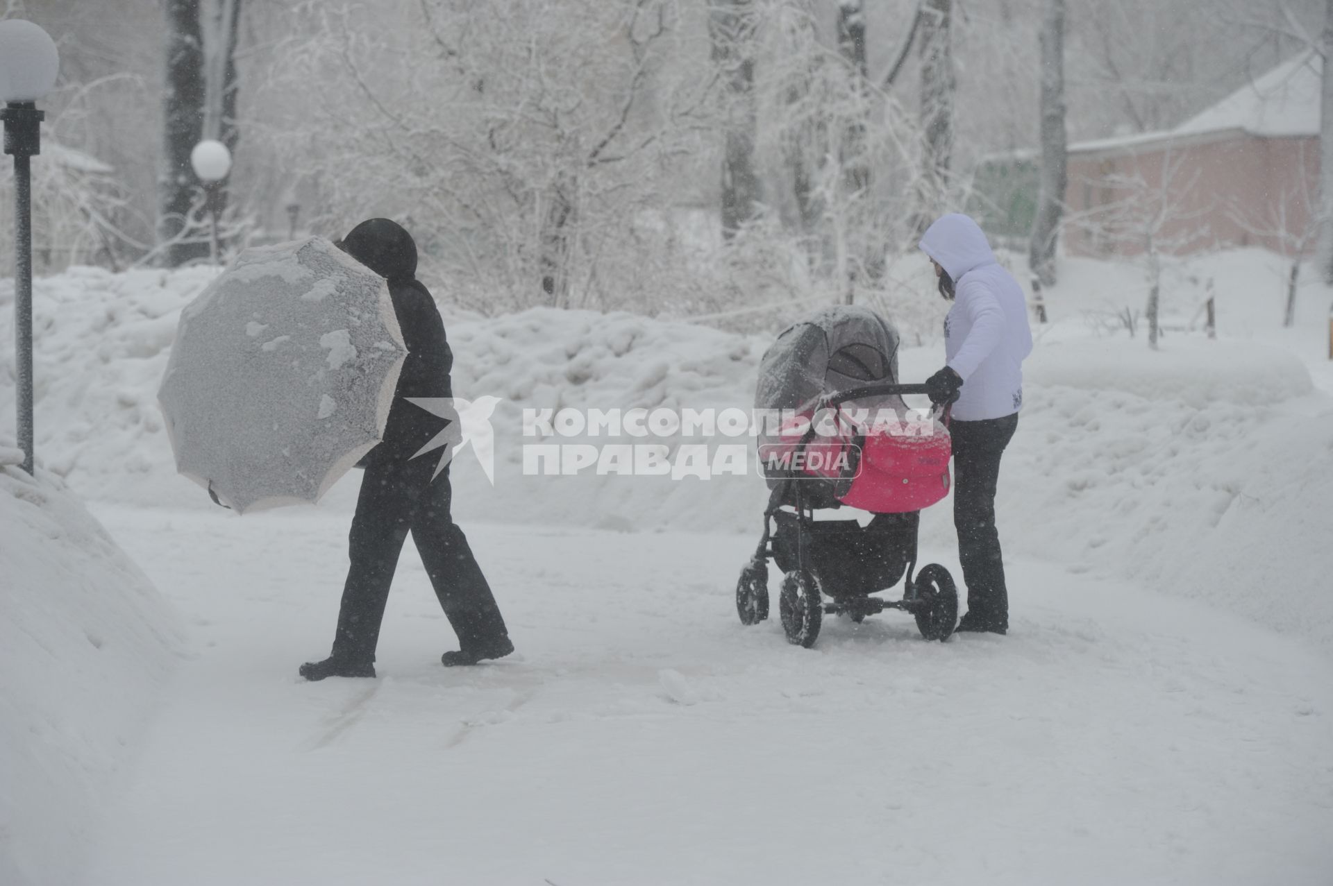 Снегопад. На снимке: женщина с детской коляской на улице города.