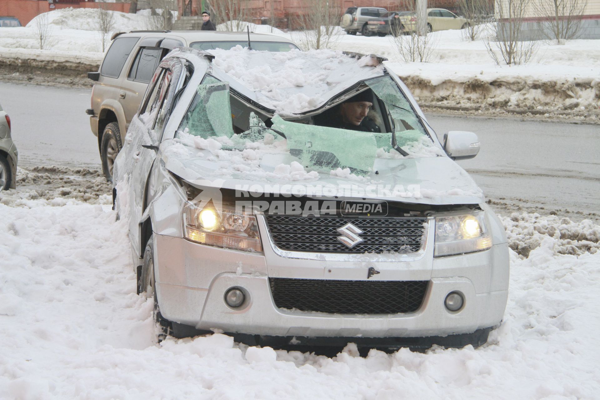 Снежная лавина обрушилась с крыши дома на тротуар и припаркованные автомобили в Барнауле. На снимке: мужчина заводит засыпанный снегом поврежденный автомобиль.