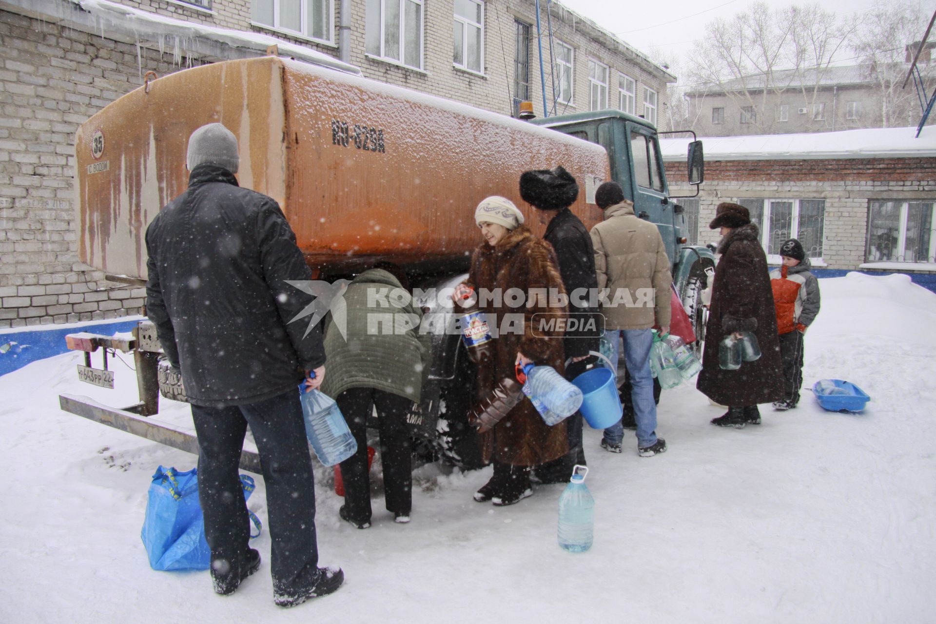 Аварийное отключение воды. На снимке: люди стоят с ведрами вокруг поливочной машины.