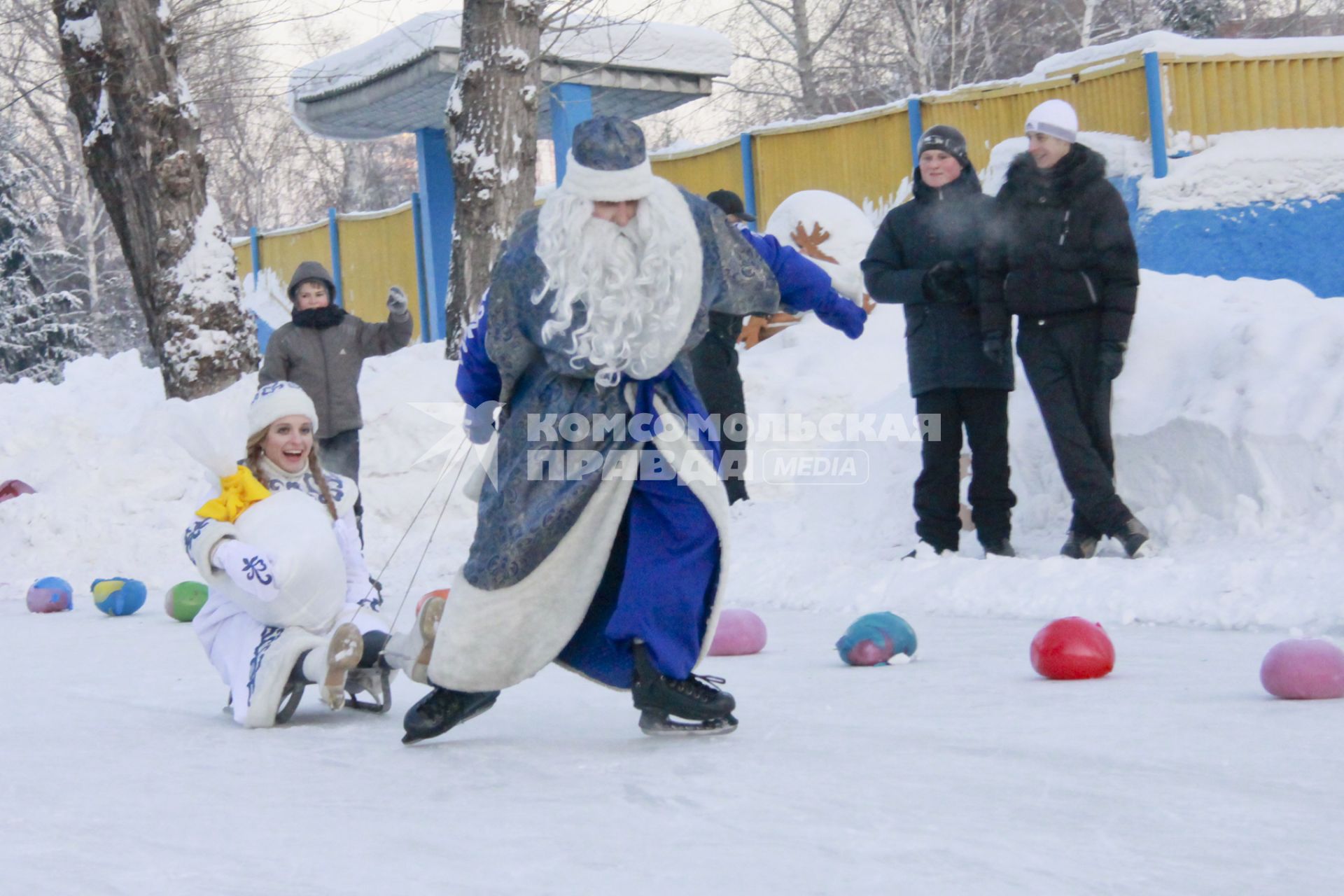 Забег Дедов Морозов на коньках. Дед мороз на коньках тащит за собой Снегурочку на санка, которая держит мешок с подарками.