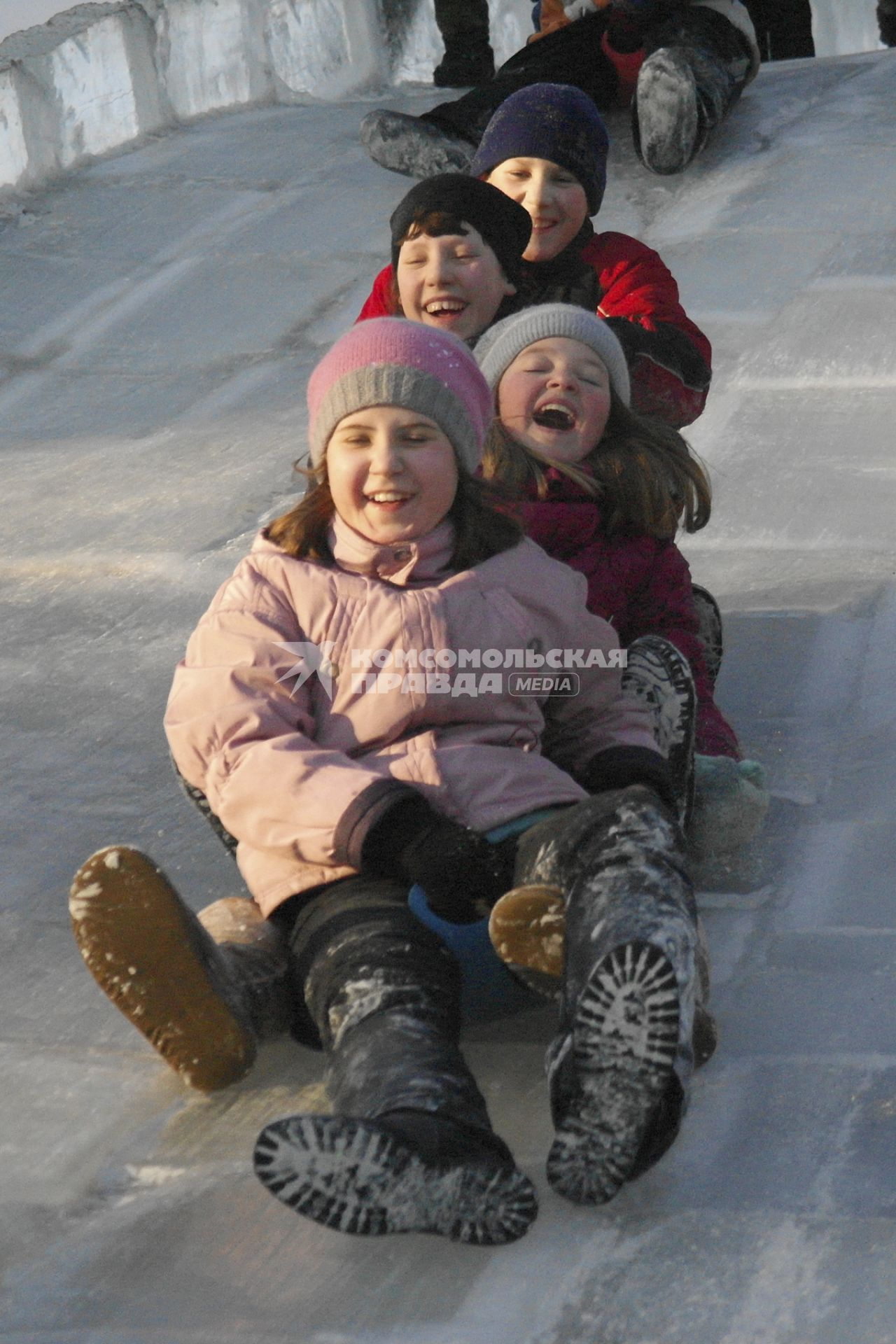 Дети катаются на ледяной горке.