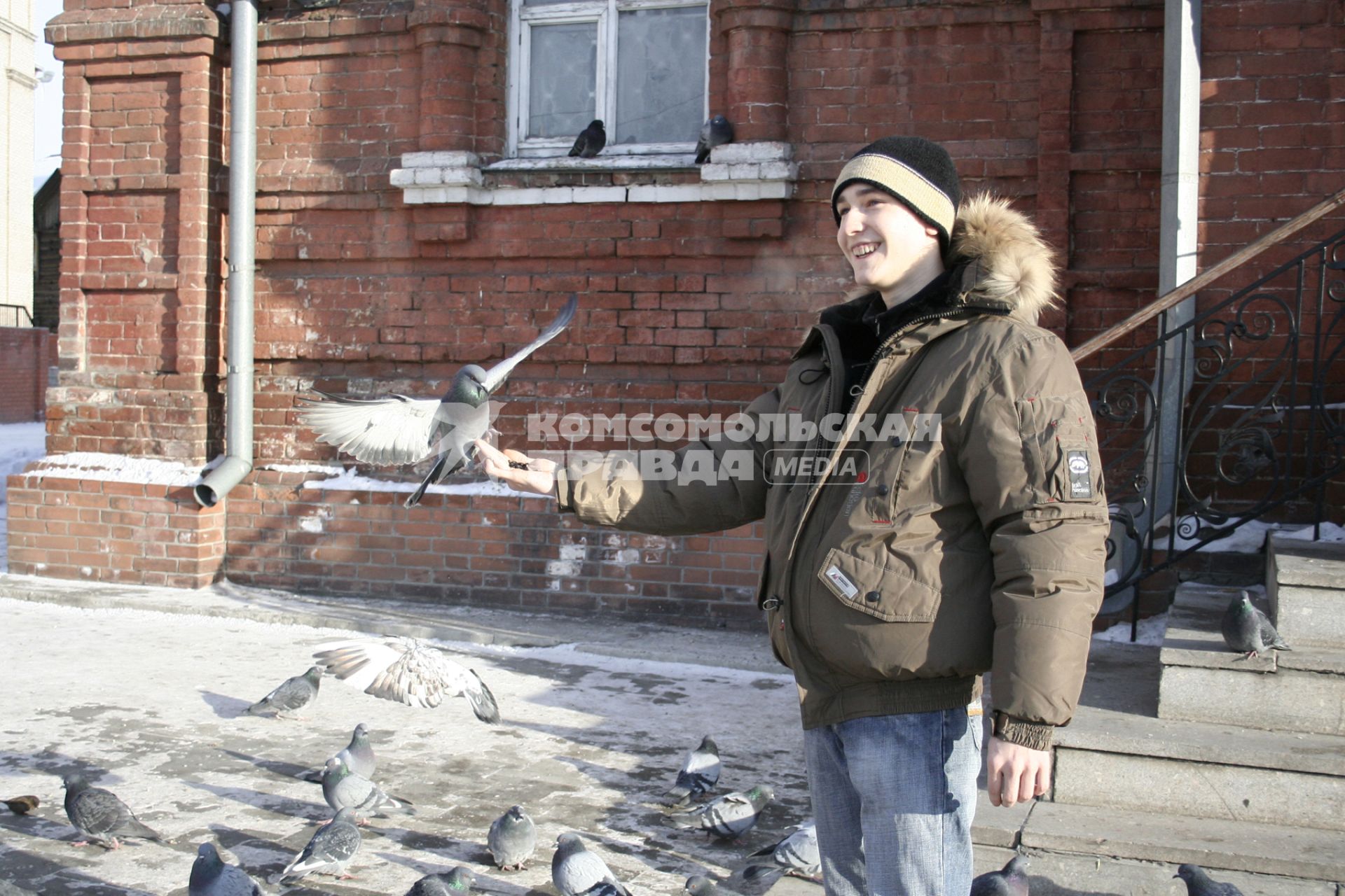 Подросток кормит голубей с рук.