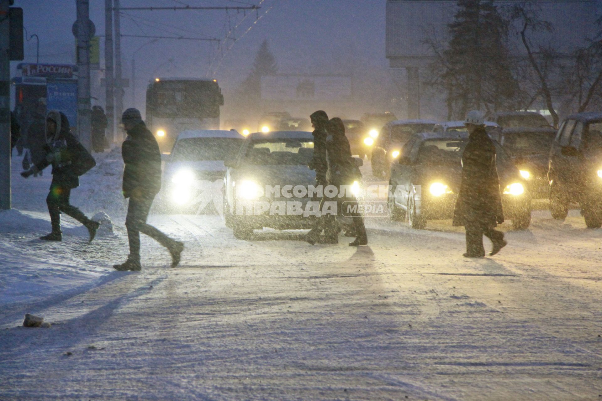 Пешеходы переходят дорогу на перекрестке во время сильного снегопада.