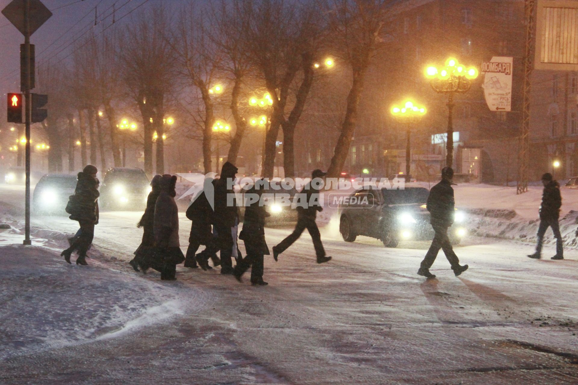 Пешеходы переходят дорогу на перекрестке во время сильного снегопада.