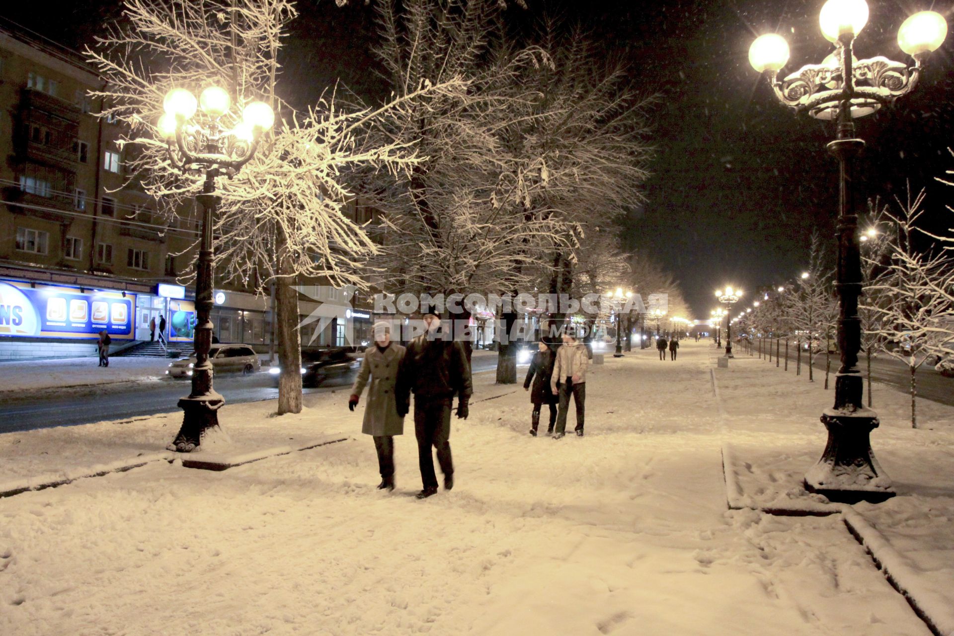 Люди гуляют по зимнему вечернему городу.