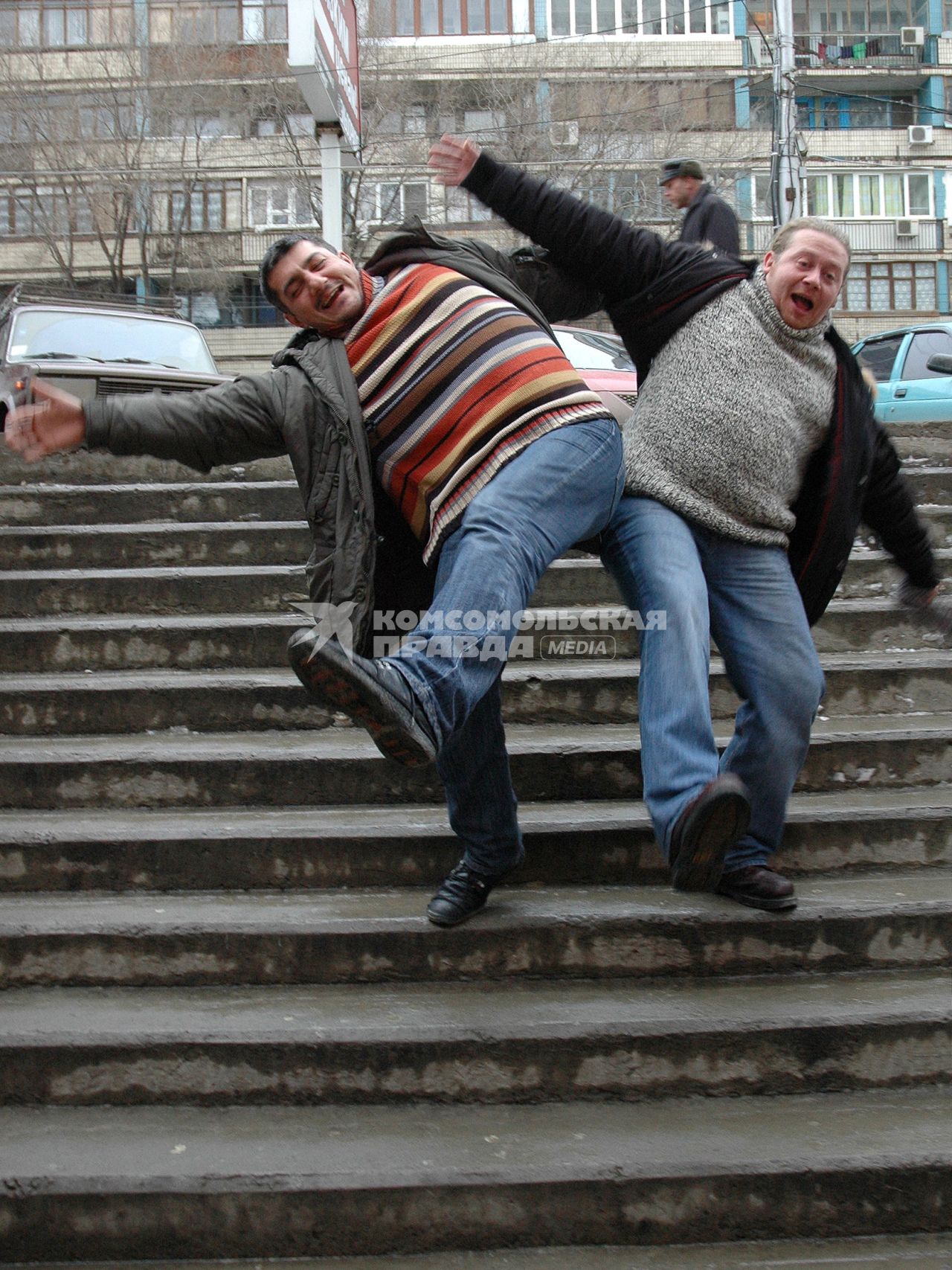 Двое мужчин поскользнулись на скользкой лестнице зимой во время гололеда.