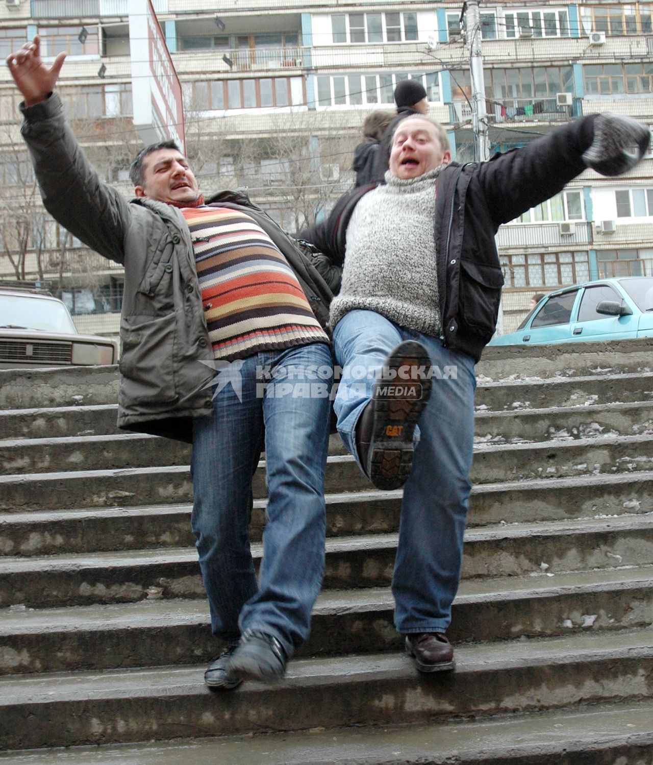 Двое мужчин поскользнулись на скользкой лестнице зимой во время гололеда.