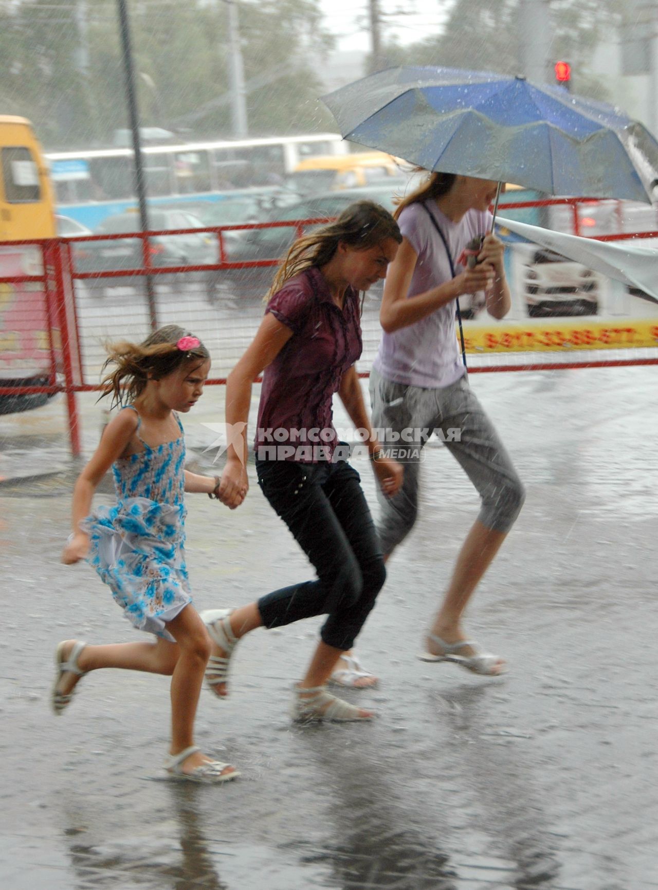 Девчонки бегут по улице под проливным дождем.