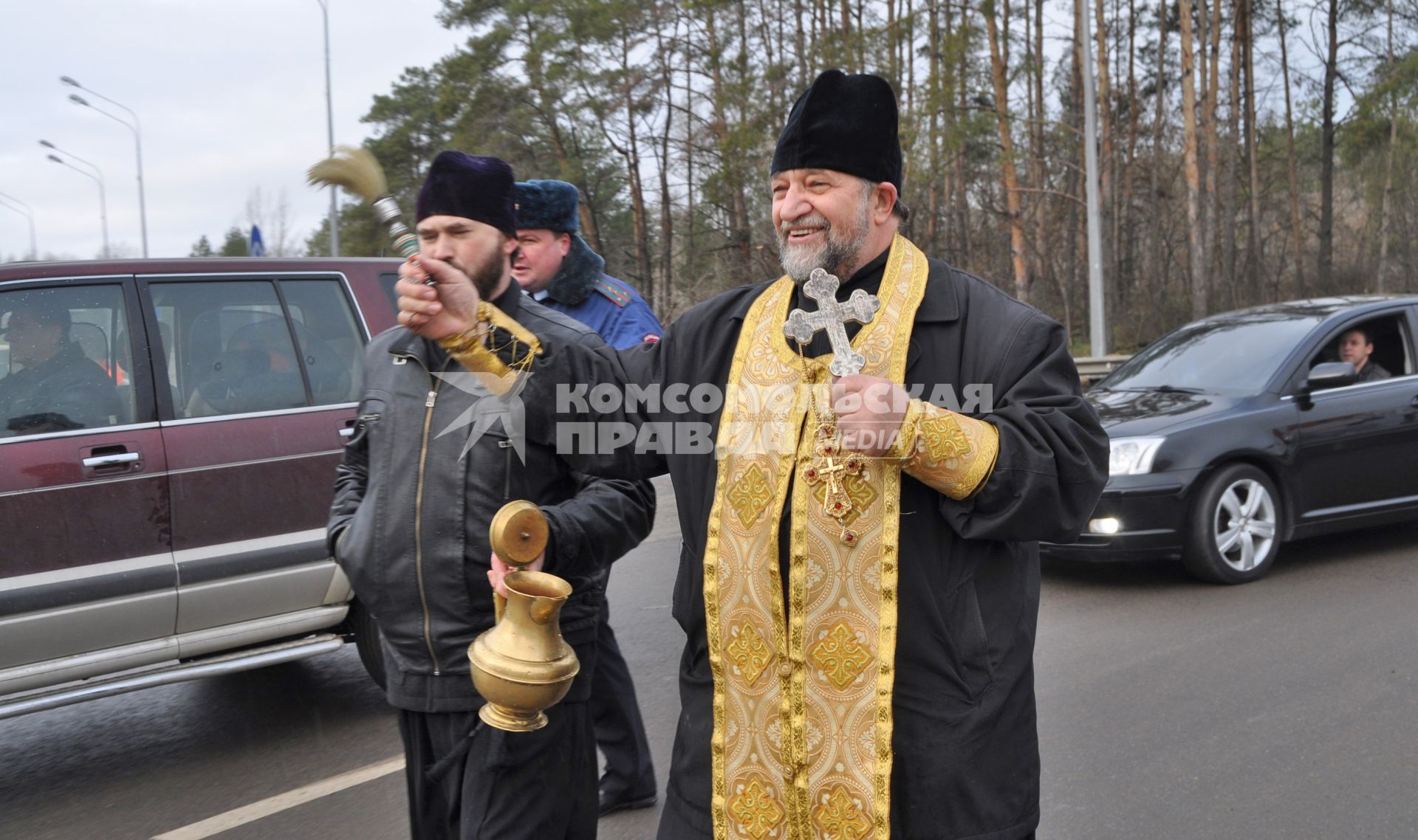 В Воронеже освятили одно из самый аварийных мест города - кольцо на улице Антонова-Овсеенко. На снимке: священник идет по дороге, освящая ее с помощью святой воды.