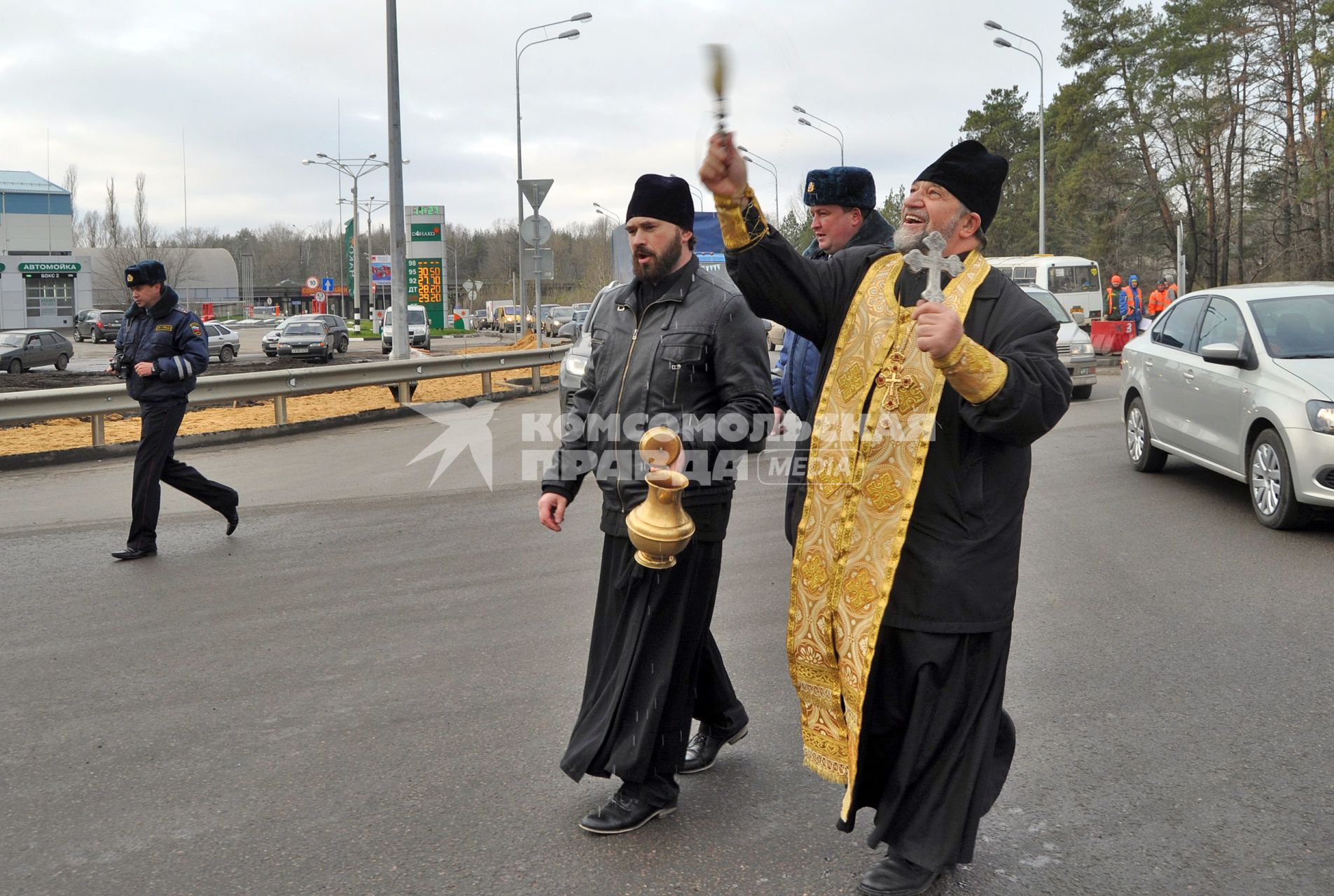 В Воронеже освятили одно из самый аварийных мест города - кольцо на улице Антонова-Овсеенко. На снимке: священник идет по дороге, освящая ее с помощью святой воды.