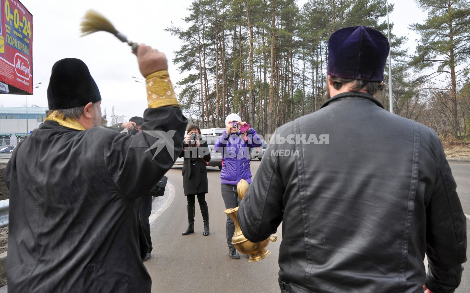 В Воронеже освятили одно из самый аварийных мест города - кольцо на улице Антонова-Овсеенко. На снимке: священник идет по дороге, освящая ее с помощью святой воды.