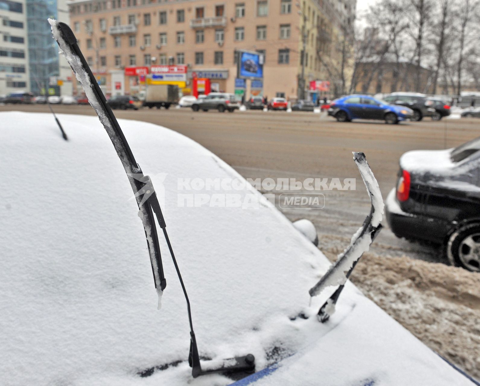 Последствия снегопада.На снимке: автомобильные дворники на заснеженной машине.