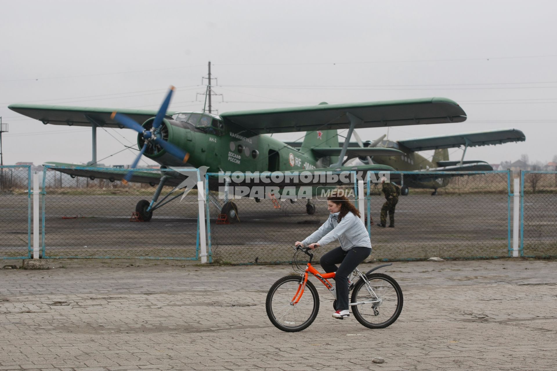 Самолет Ан-2 на аэродроме \"Девау\" в Калининграде, девушка на велосипеде