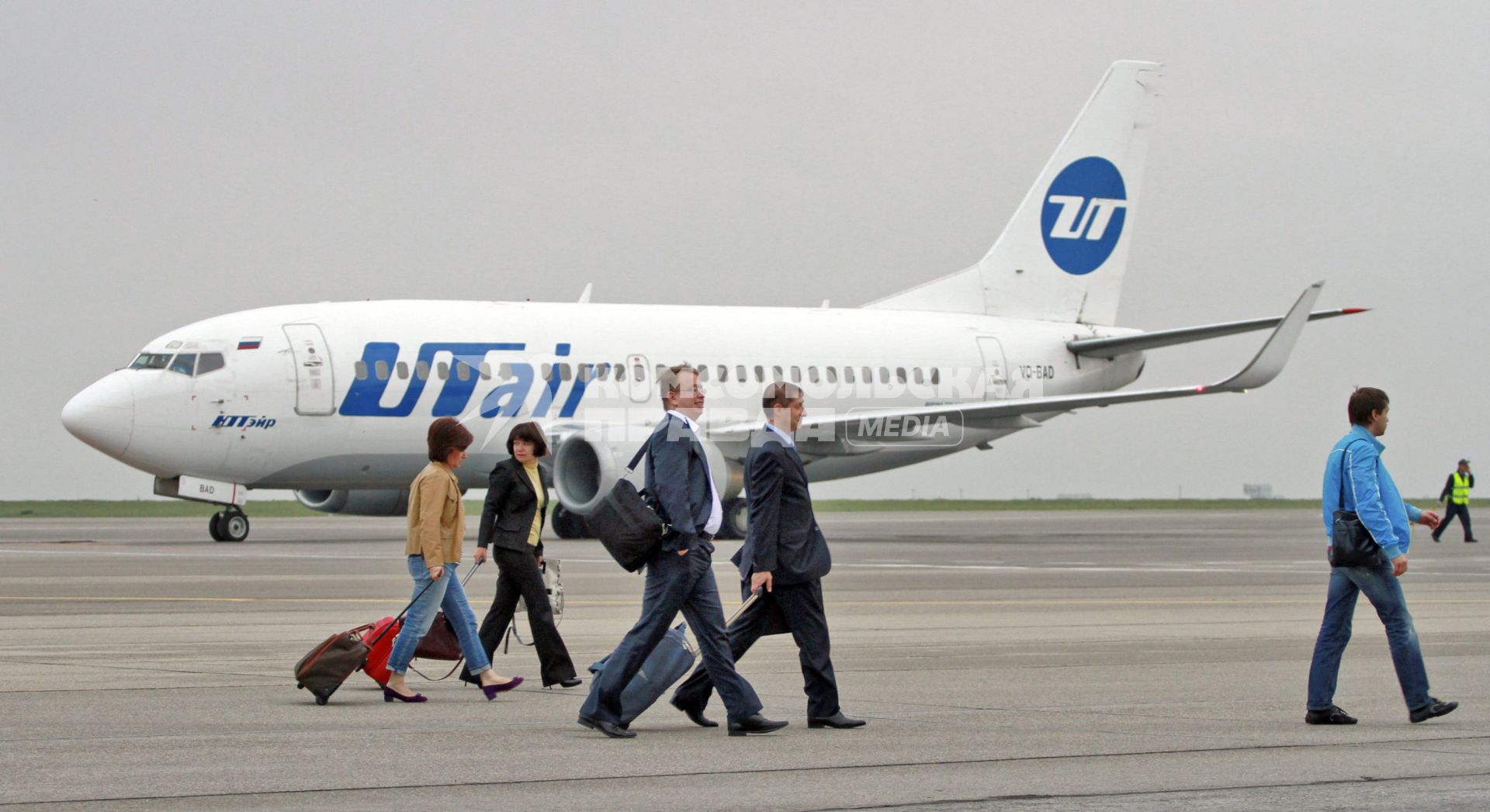 Пассажирский самолет Boeing 737-500 авиакомпания `UTair`. Пассажиры идут по взлетной полосе.