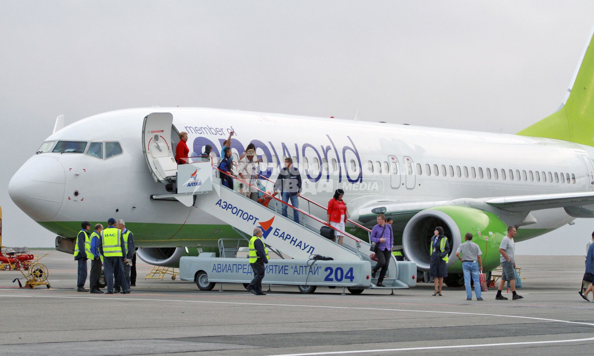 Пассажиры спускаются по трапу покидая самолет Боинг 737-800 авиакомпании `S7`.