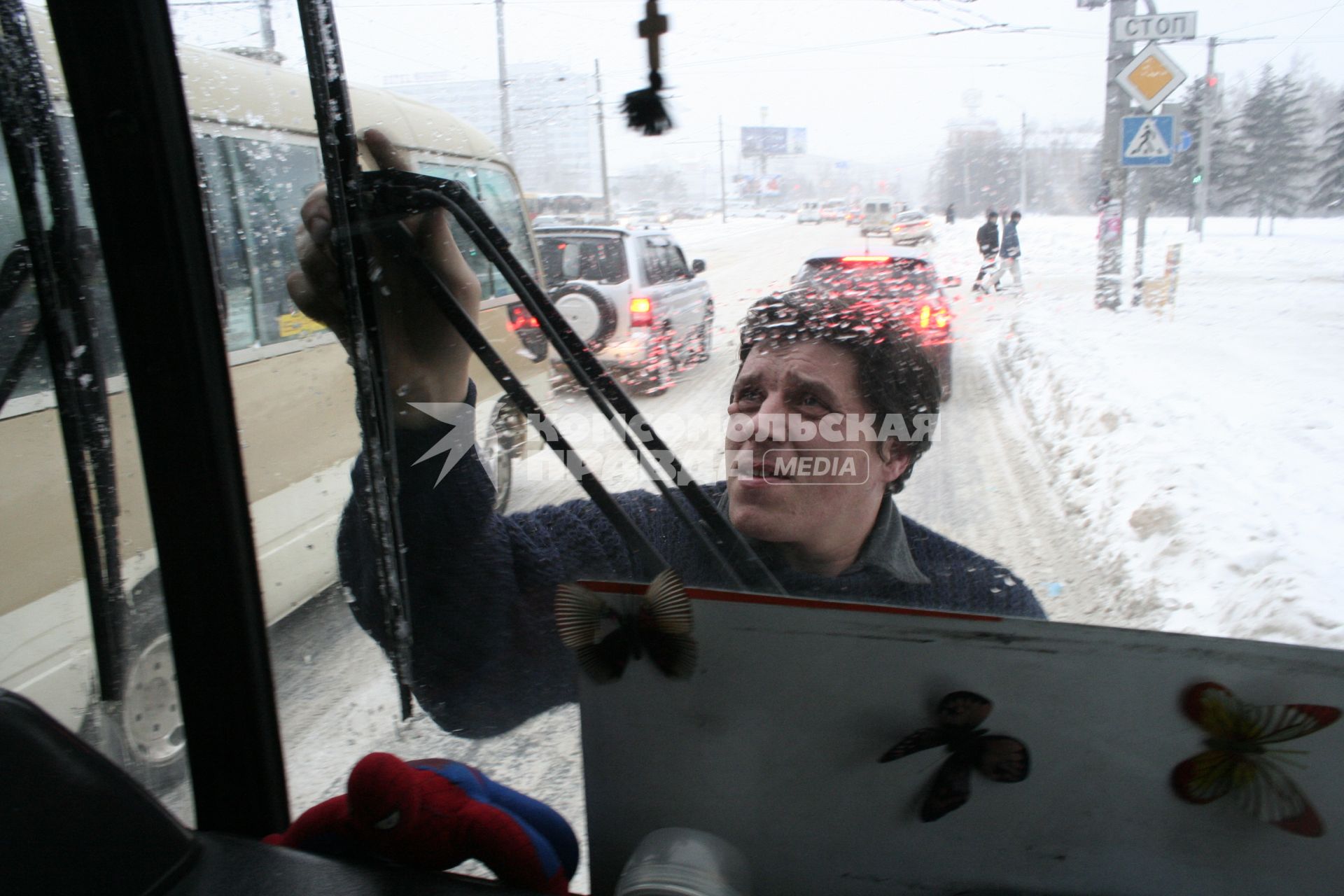 Водитель автобуса чистит дворники.