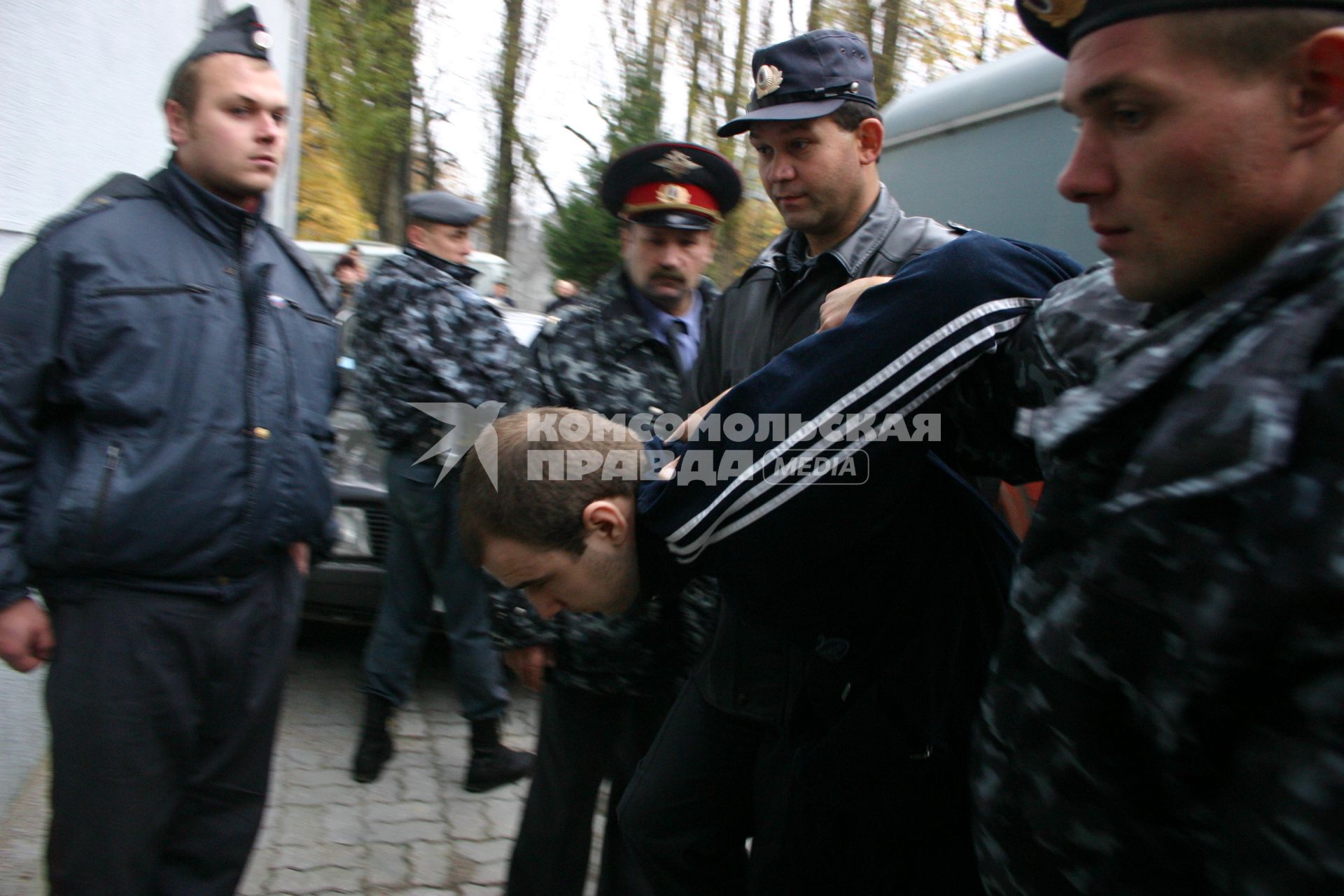 Полицейские полицейские выводят нарушителя из здания суда