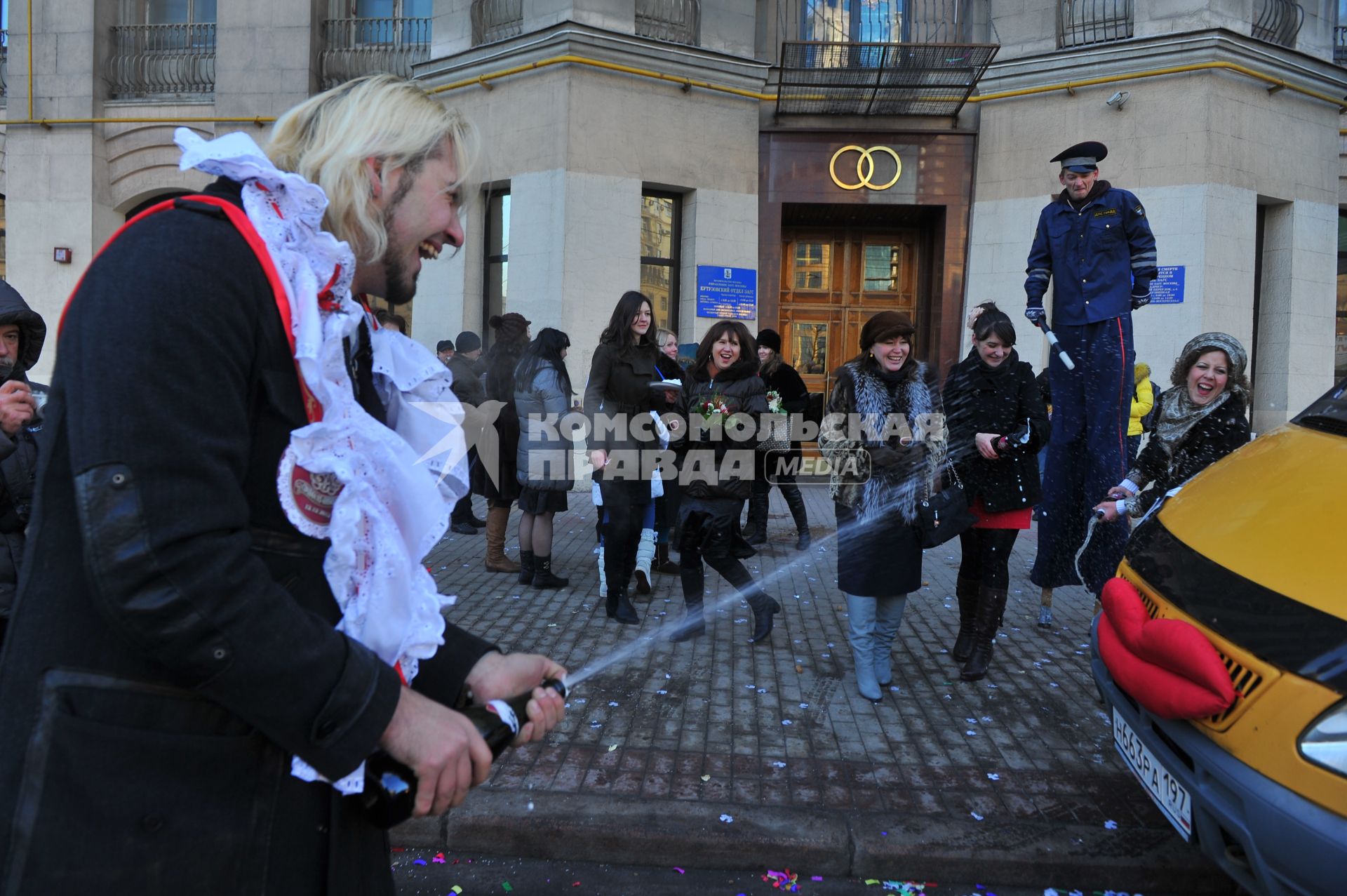 Креативная свадьба 12.12.12. На снимке: молодой человек обливает свадебную `Газель` шампанским.