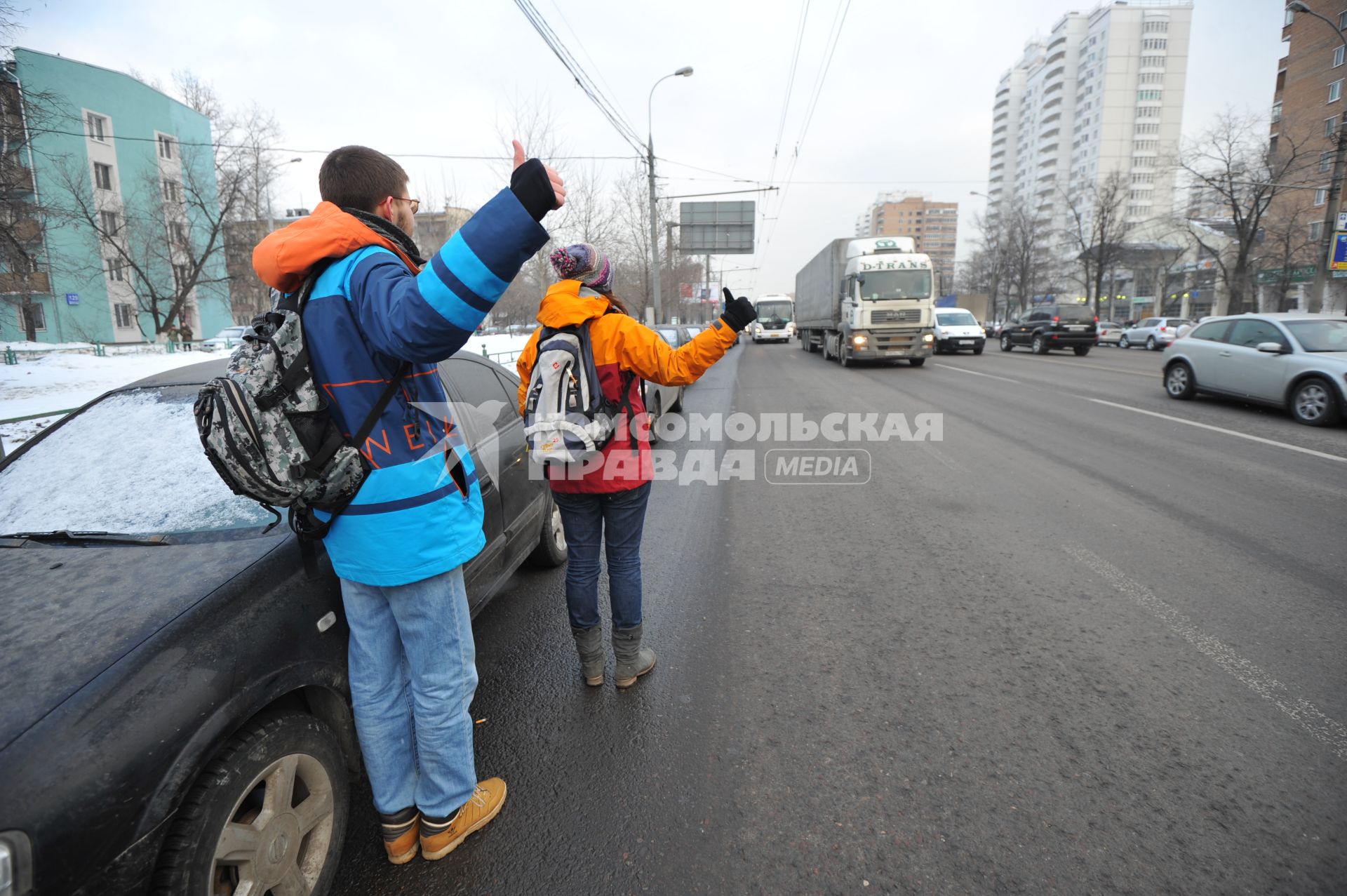 Путешествие автостопом. На снимке: молодые люди голосуют на шоссе.