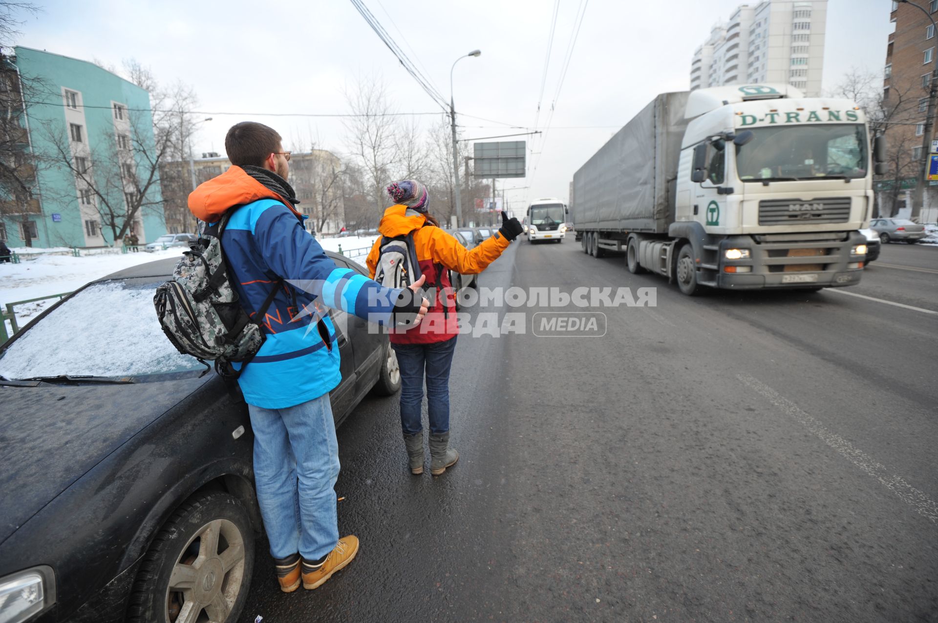 Путешествие автостопом. На снимке: молодые люди голосуют на шоссе.