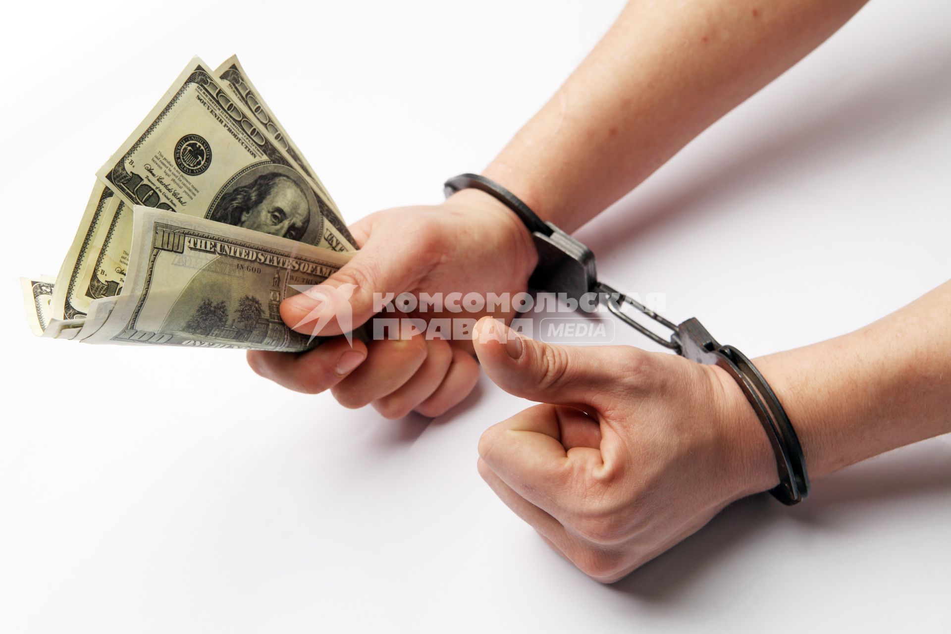Руки с деньгами в наручниках.