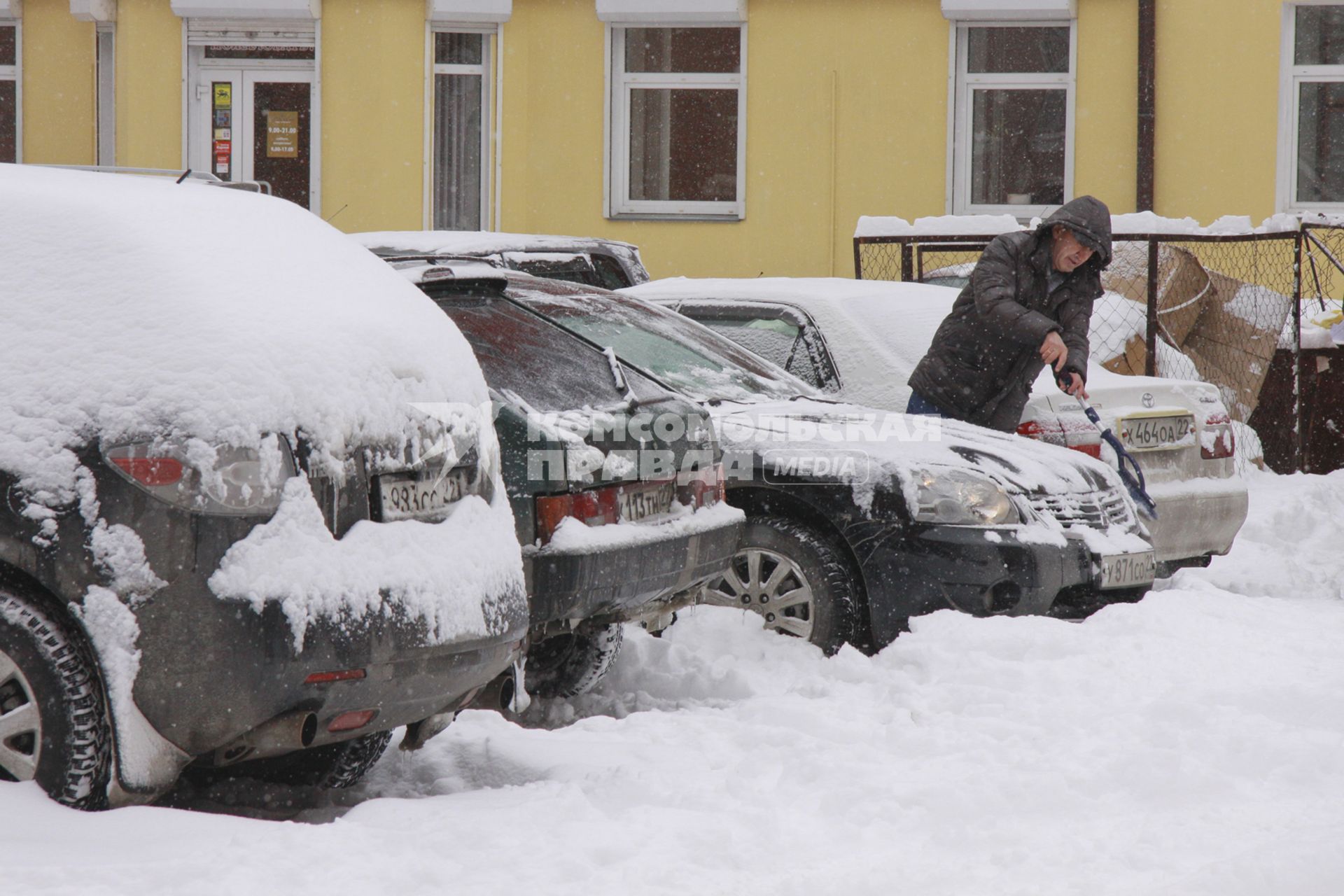 Водитель чистит автомобиль от снега.