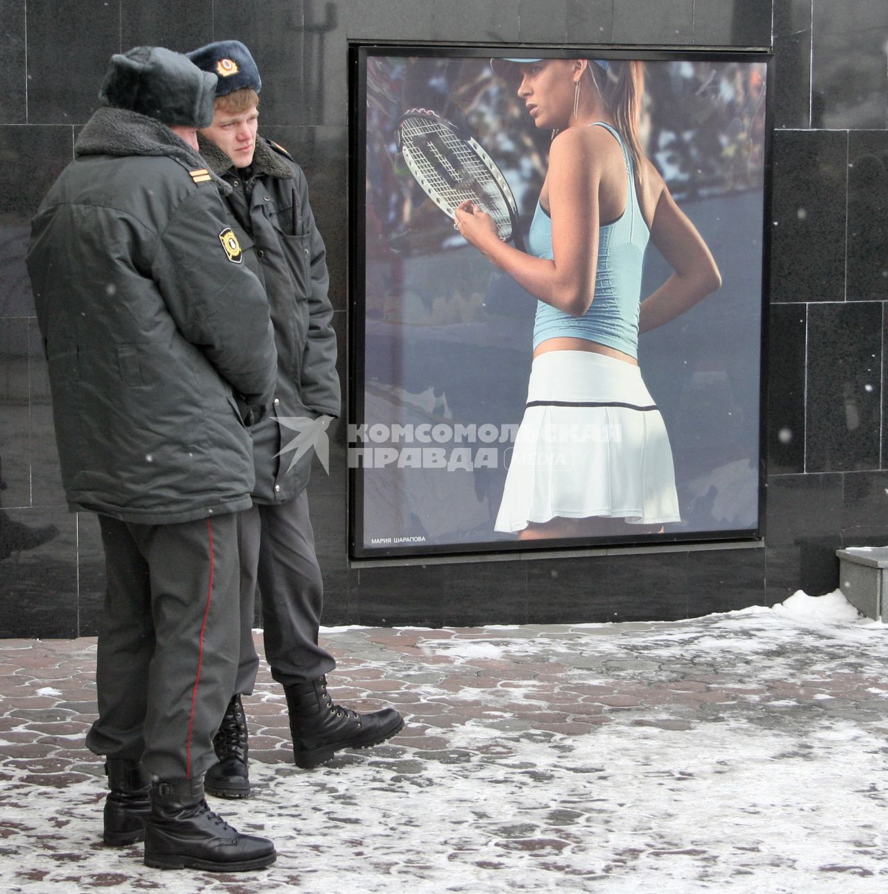Полицейские зимой жмутся от холода рядом с рекламным щитом на котором изображена теннисистка Мария Шарапова.