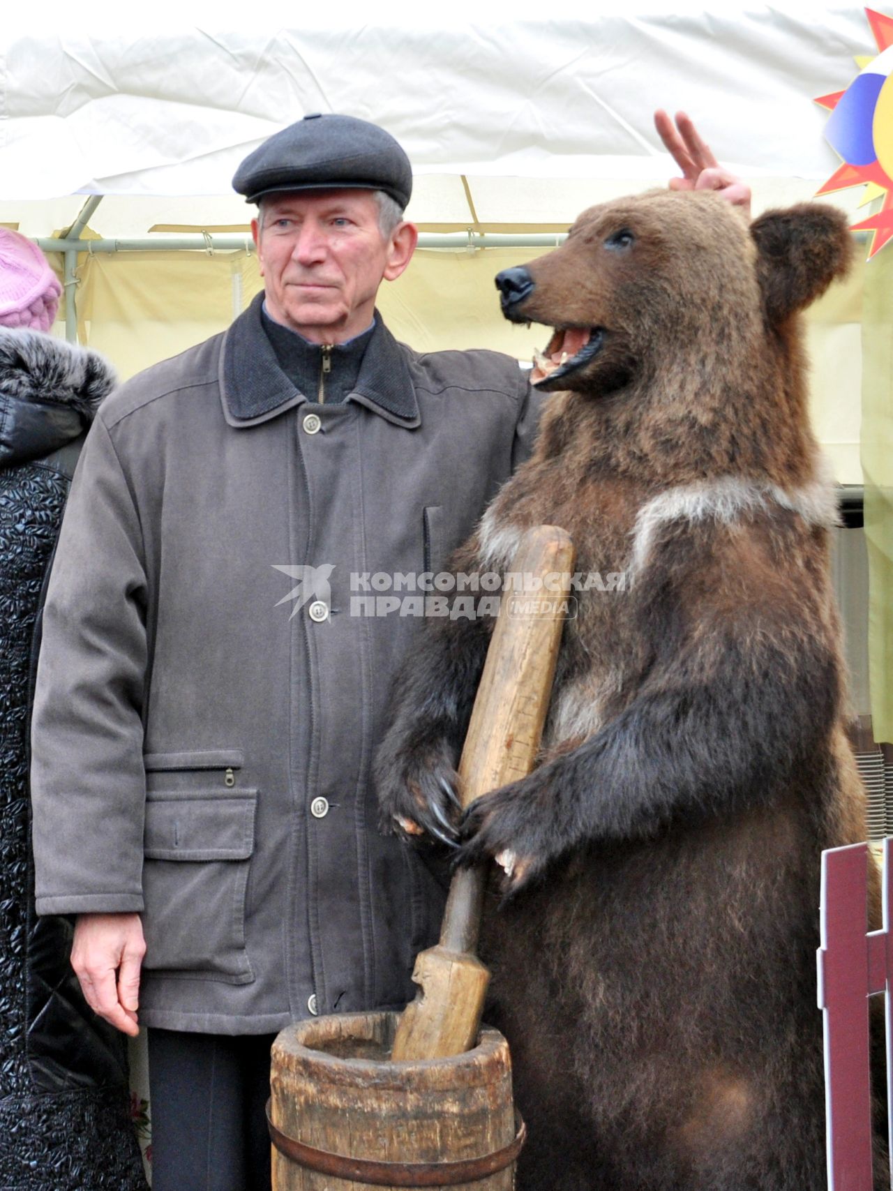 Мужчина фотографируется с чучелом медведя.