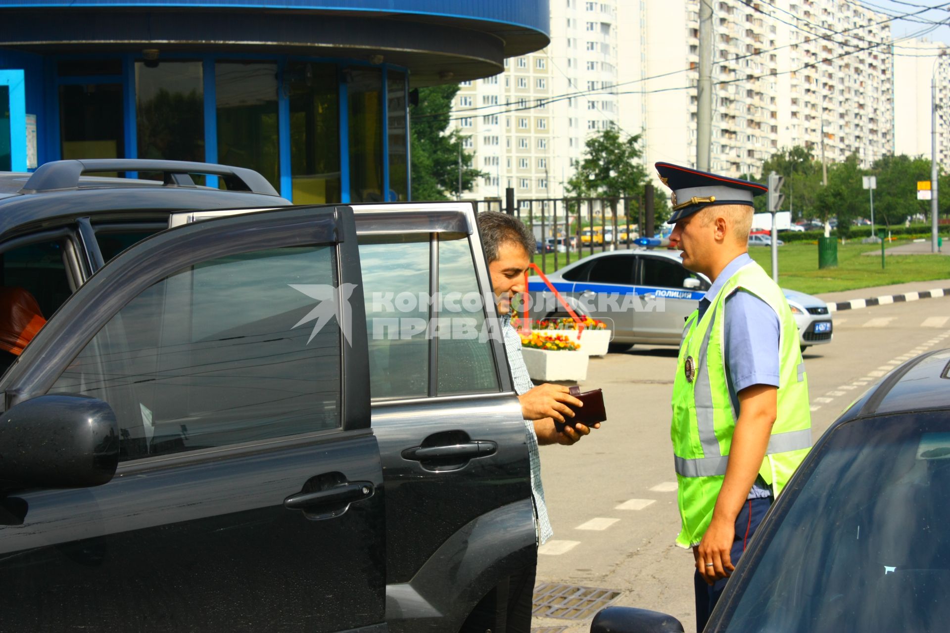 Сотрудник ДПС проверяет документы у водителя автомобиля с тонированными стеклами.