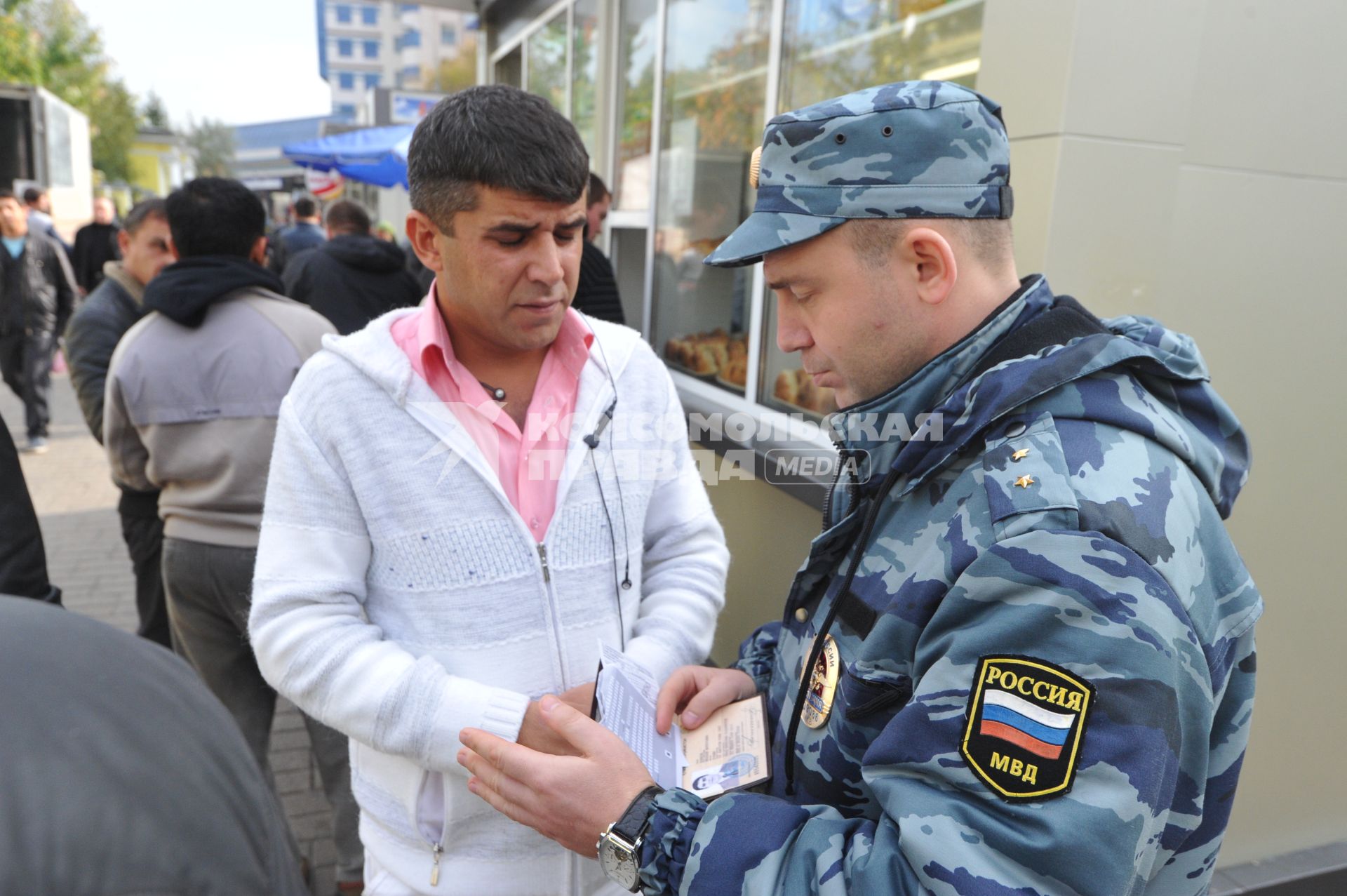 ОМОНовец проверяет документы у мигранта.