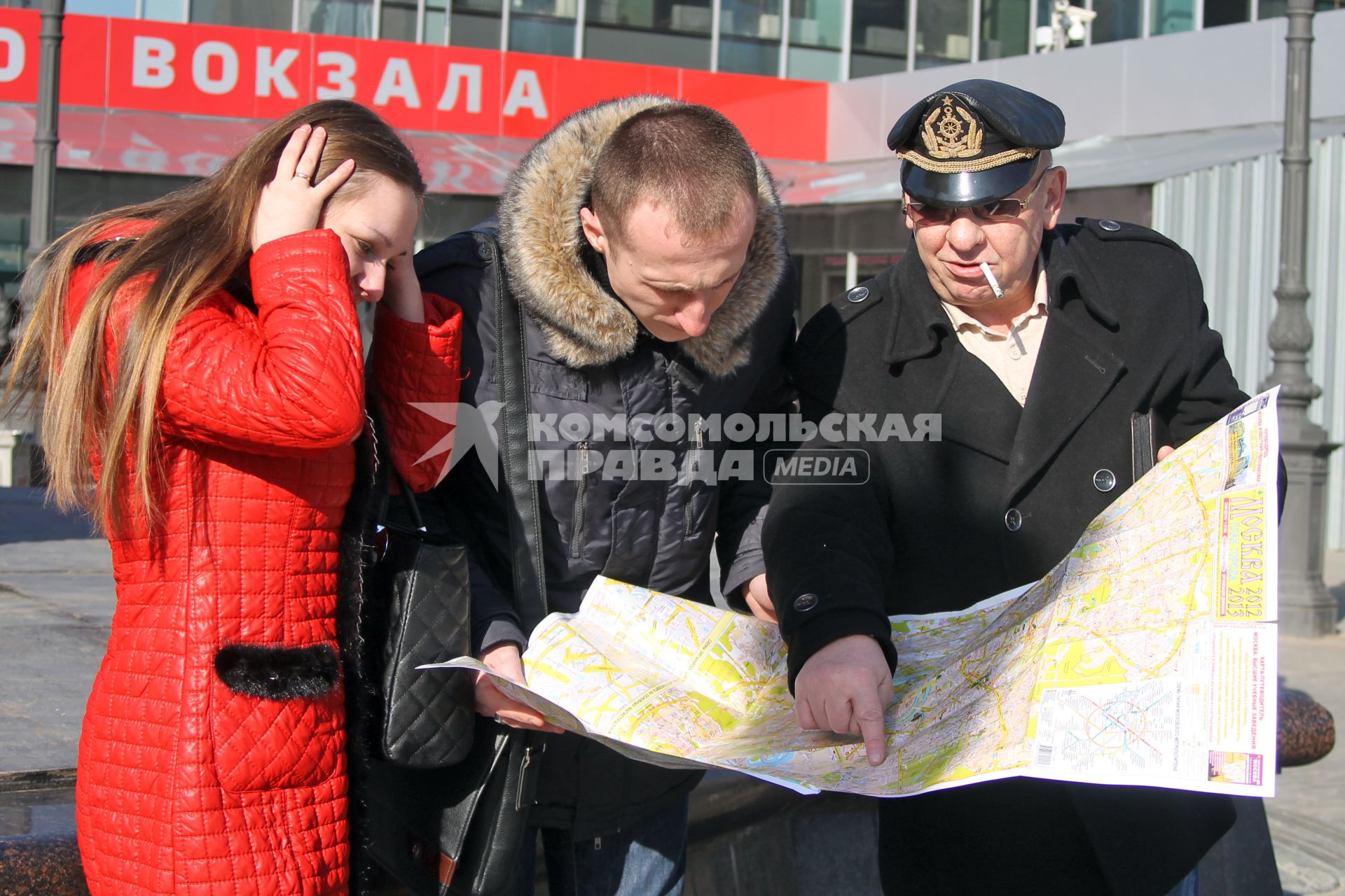 Три человека около вокзала изучают карту Москвы.