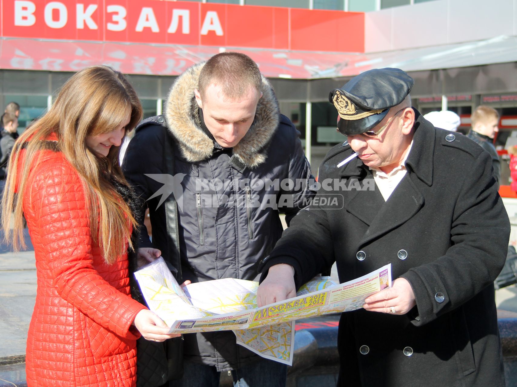 Три человека около вокзала изучают карту Москвы.