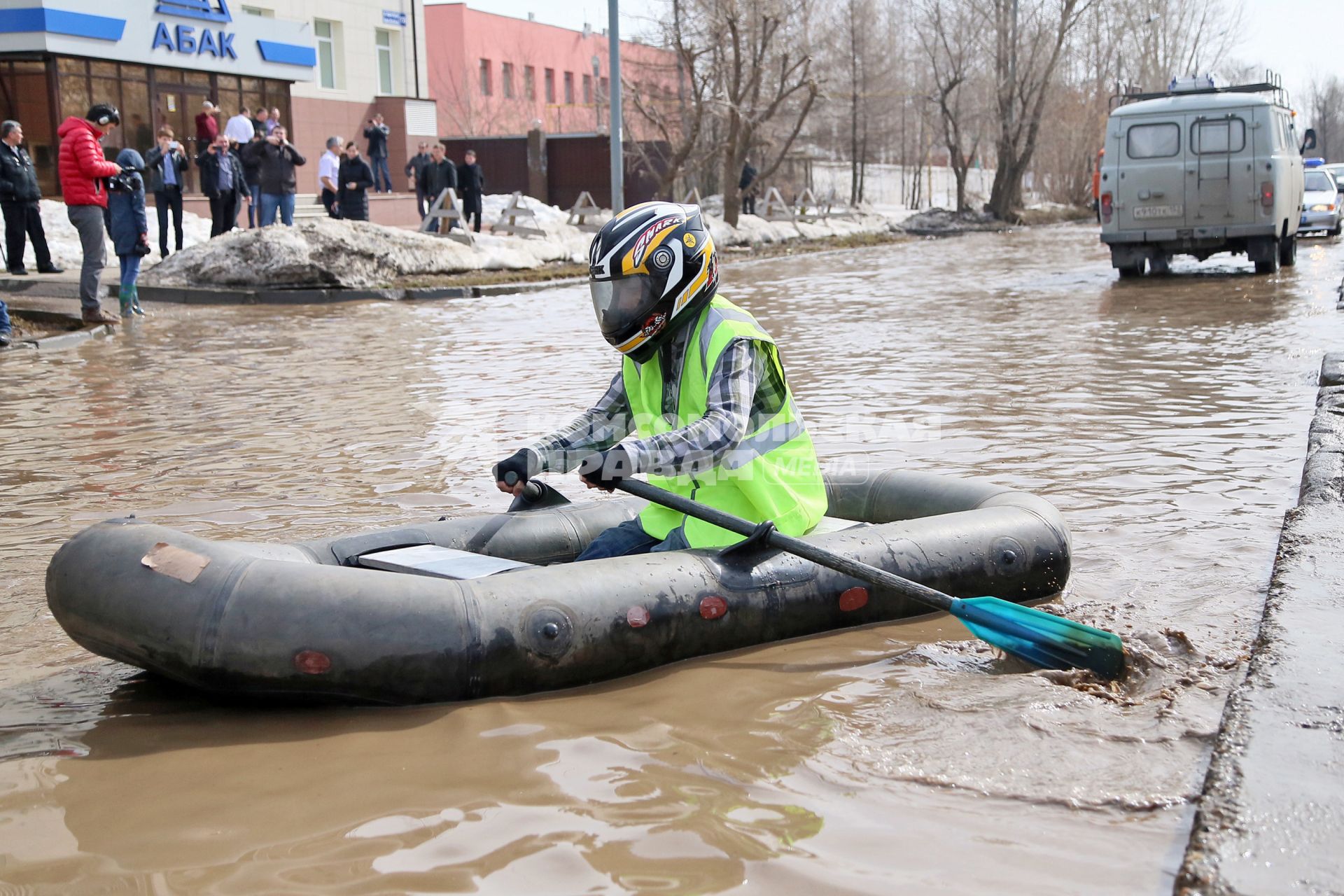 Из-за быстрого таяния снегов весенние паводковые воды затопили проезжую часть на улицах Казани. На снимке: мужчина в мотоциклетном шлеме на резиновой лодке плывет по затопленной улице города.