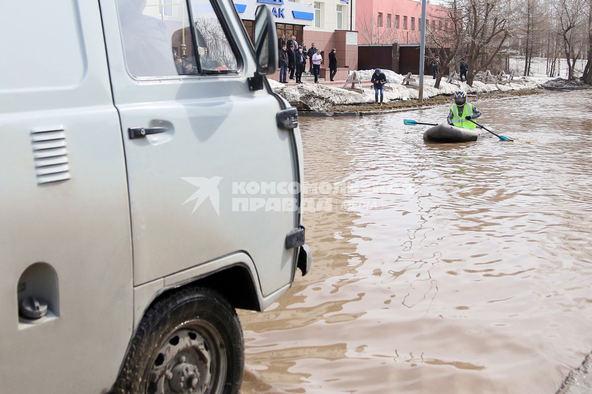 Из-за быстрого таяния снегов весенние паводковые воды затопили проезжую часть на улицах Казани. На снимке: мужчина в мотоциклетном шлеме на резиновой лодке плывет по затопленной улице города.