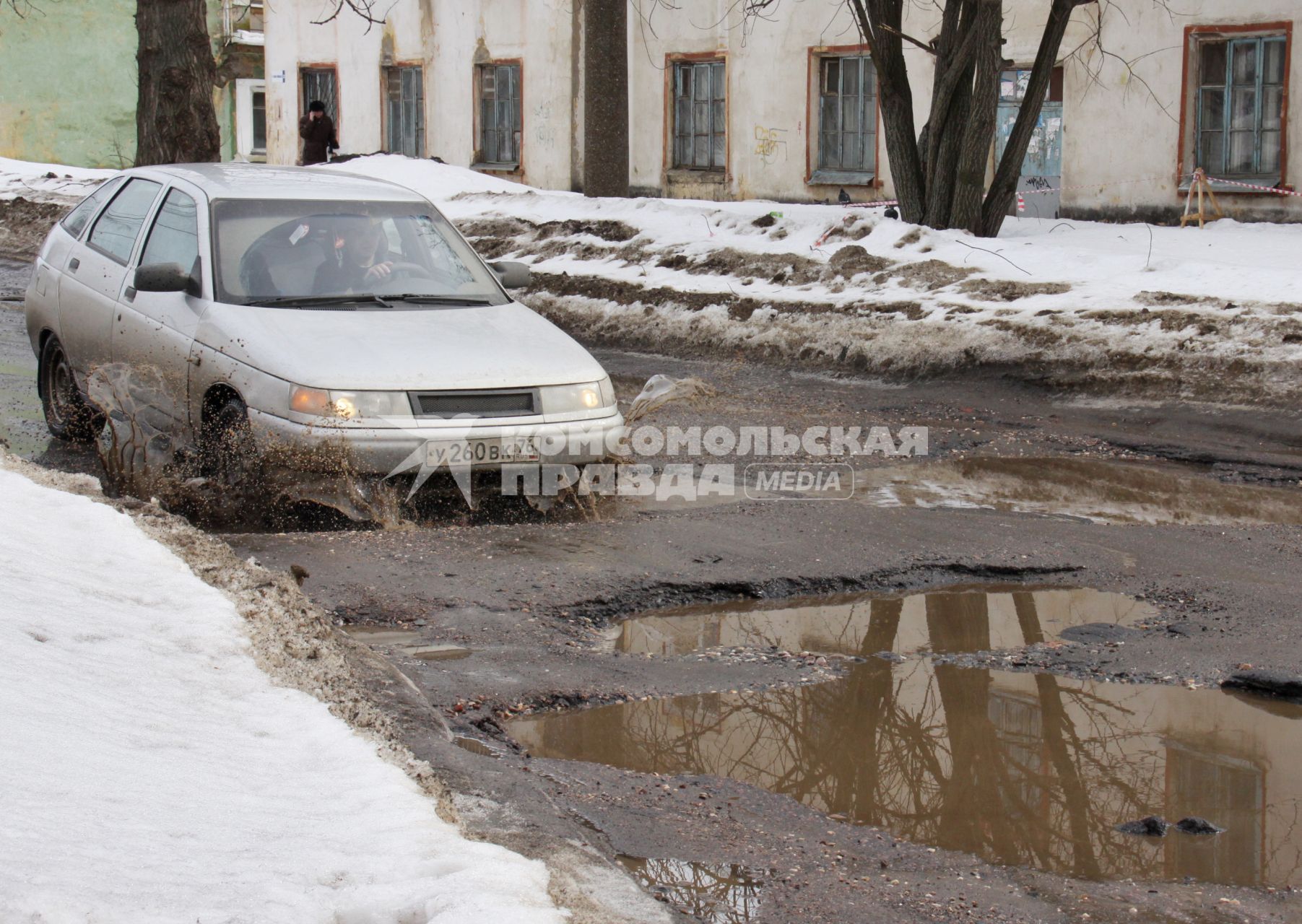 Ямы на дорогах в городе, автомобиль едет по ямам.