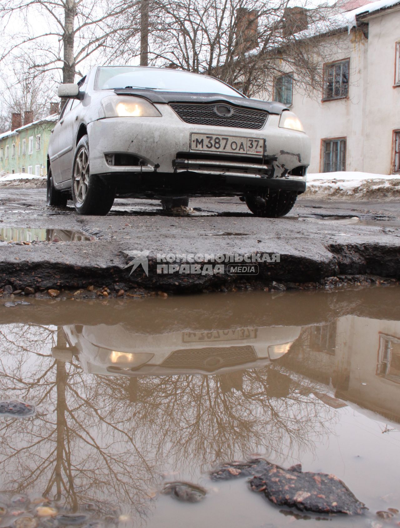 Ямы на дорогах в городе, автомобиль едет по ямам.