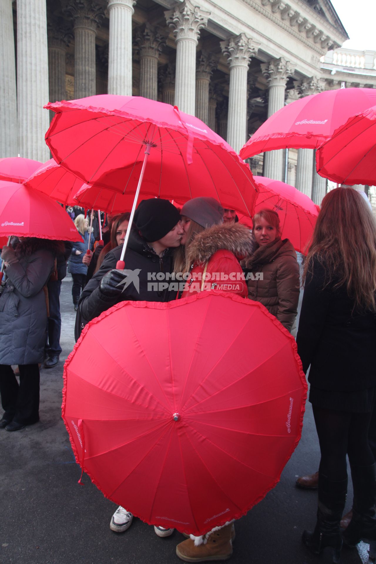 Акция в Санкт-Петербурге `Сердце города 2012` На снимке: девушка и юноша целуются стоя под красным зонтом в форме сердца.