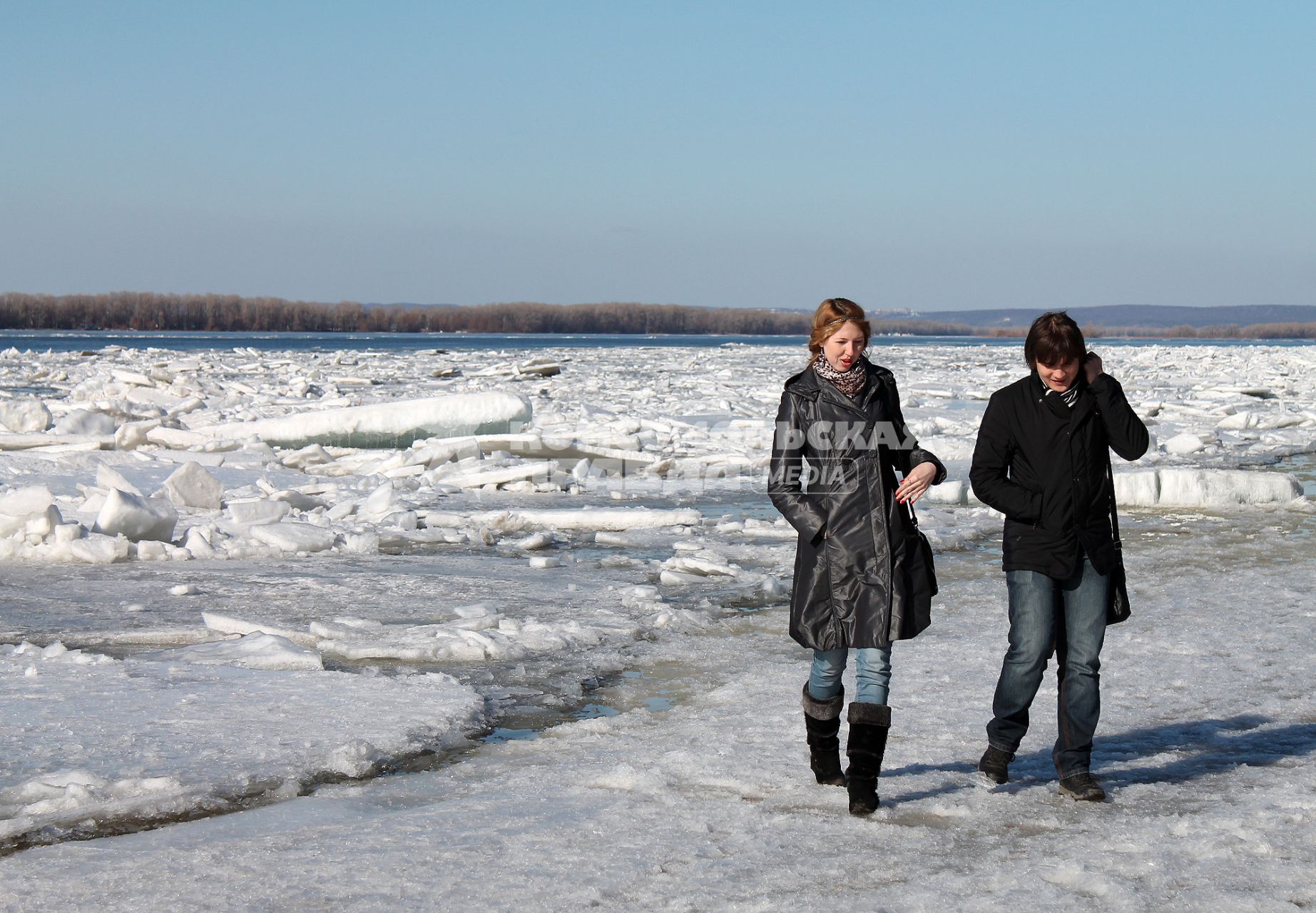 Начало ледохода на Волге. Мужчина и женщина идут по льду реки.
