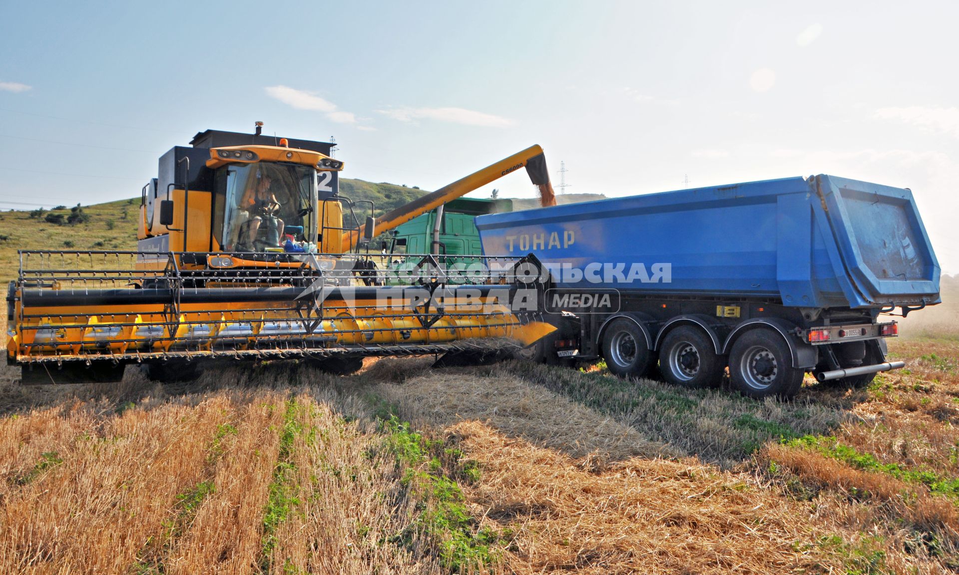 Уборка урожая. Зерноуборочный комбайн `New Holland CS 6090` и рефрижератор `МАЗ` ТОНАР`.